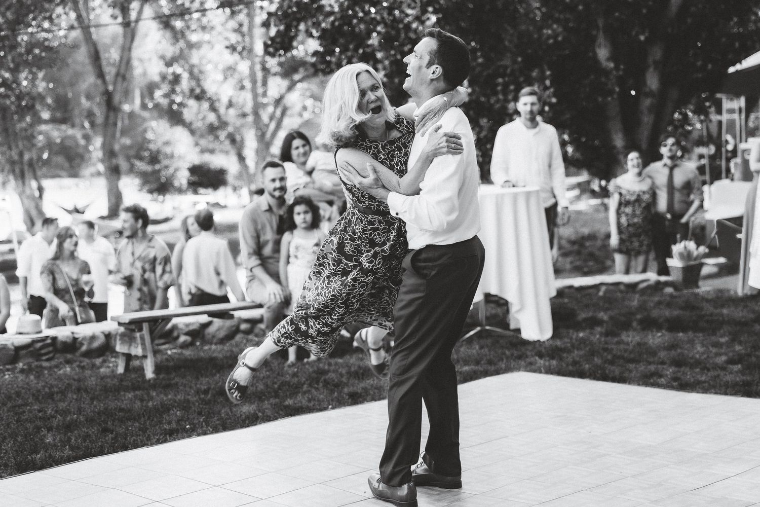 A vintage black and white photograph shows people gathered at a picnic in a park setting during the 1950s.
