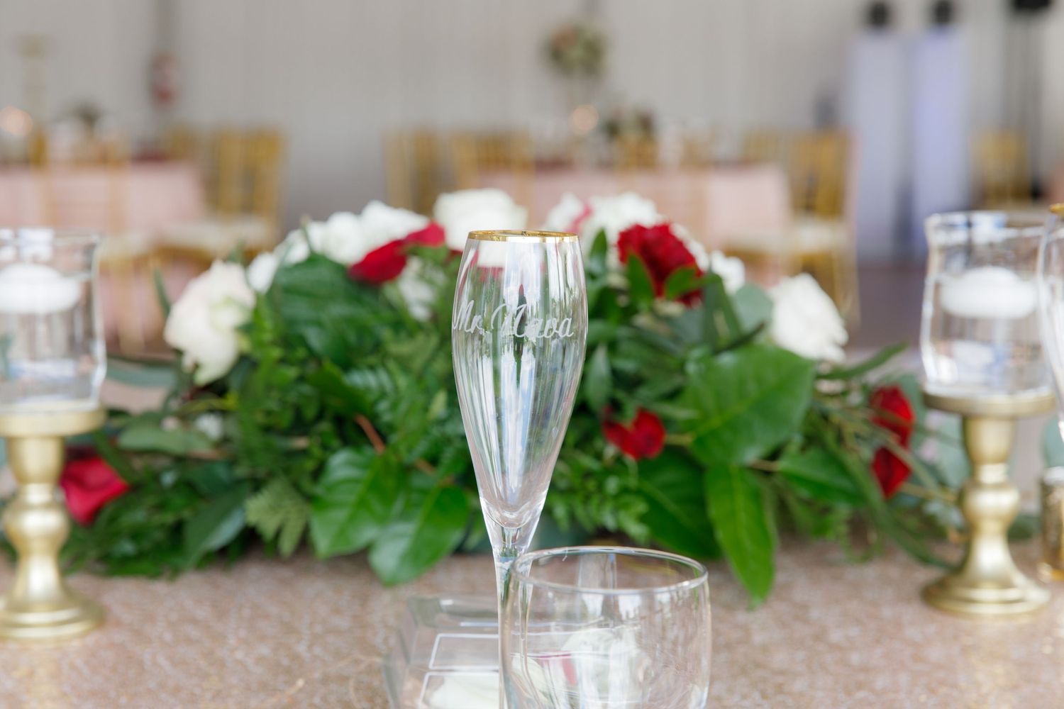 Elegant table setting with crystal glasses, candles, and red poinsettia flowers for holiday dining.