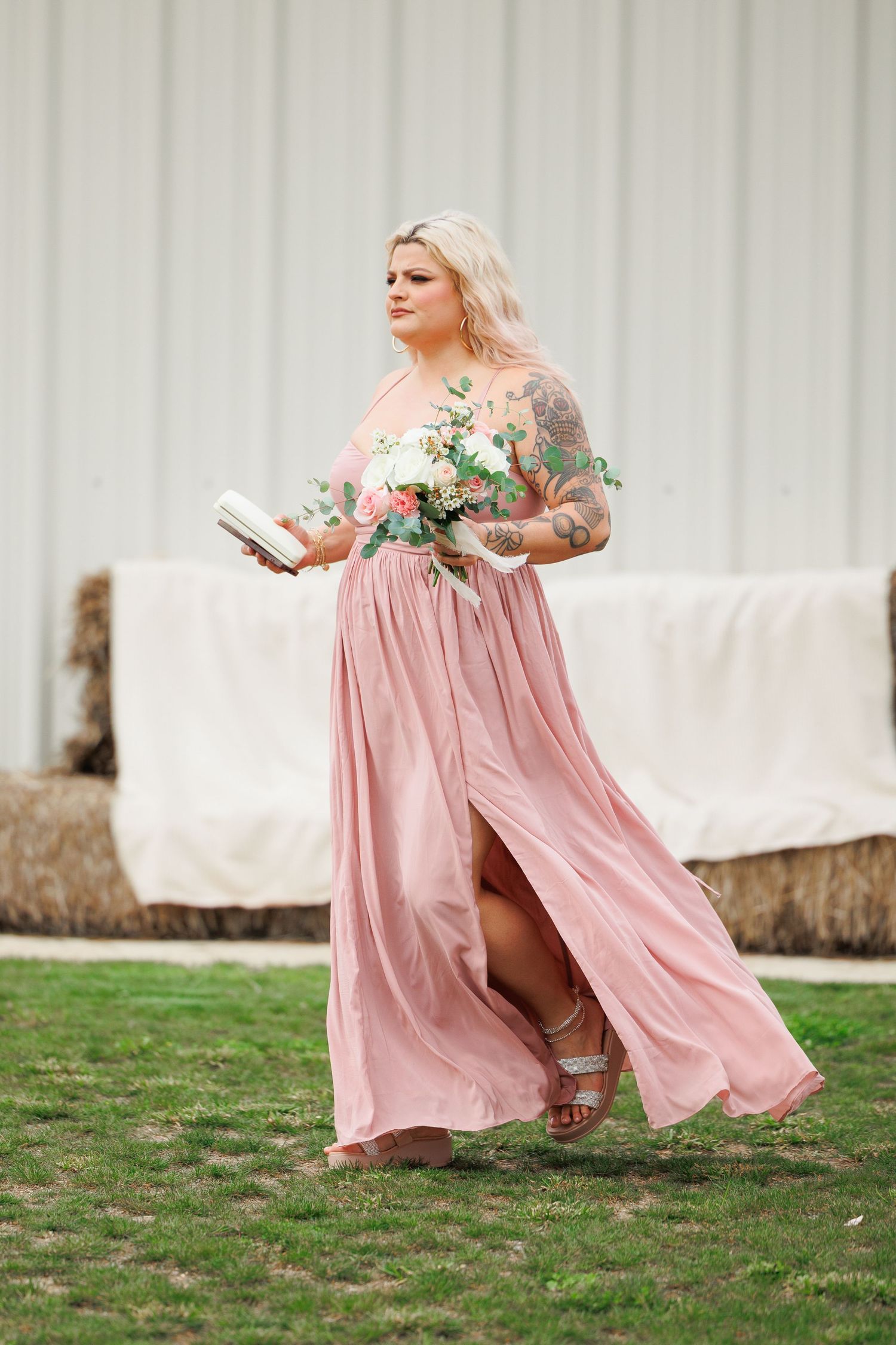 A person in a flowing pink dress twirls gracefully on a grassy lawn against a white backdrop.