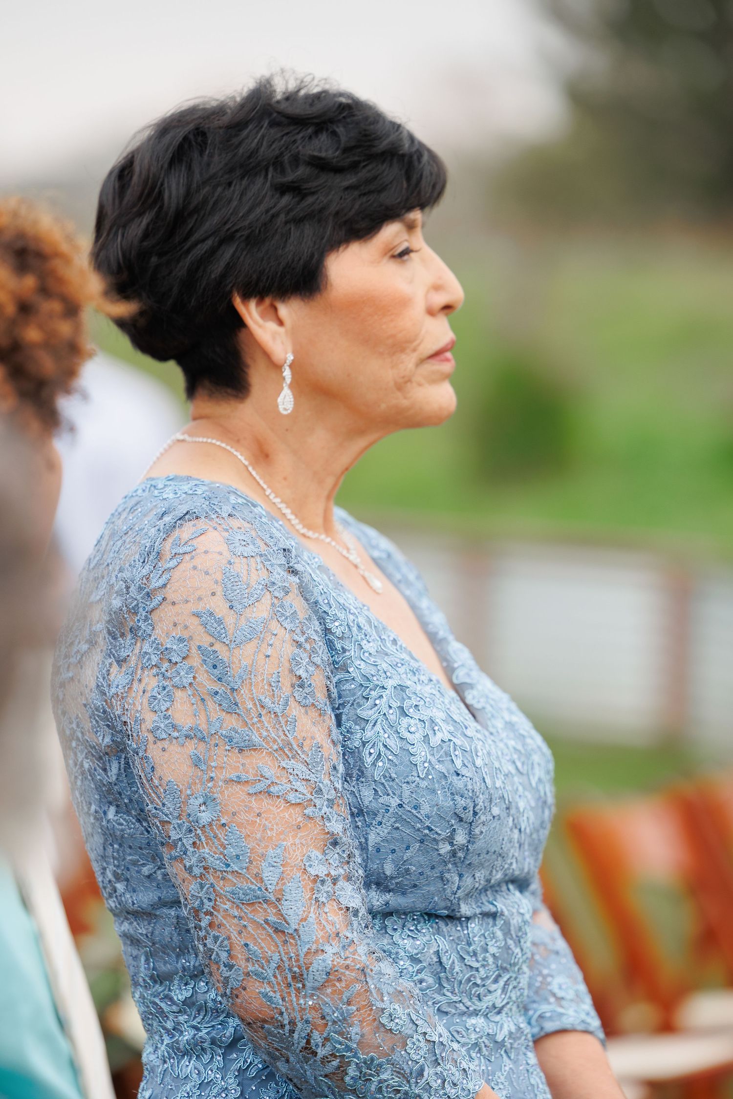 Woman in elegant light blue lace dress poses outdoors during a special occasion.