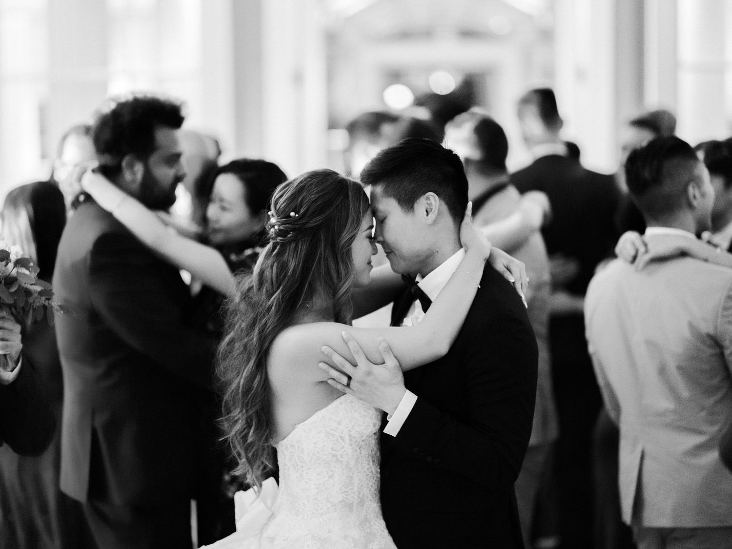 A black and white photo of a couple sharing an intimate dance moment at their wedding reception.