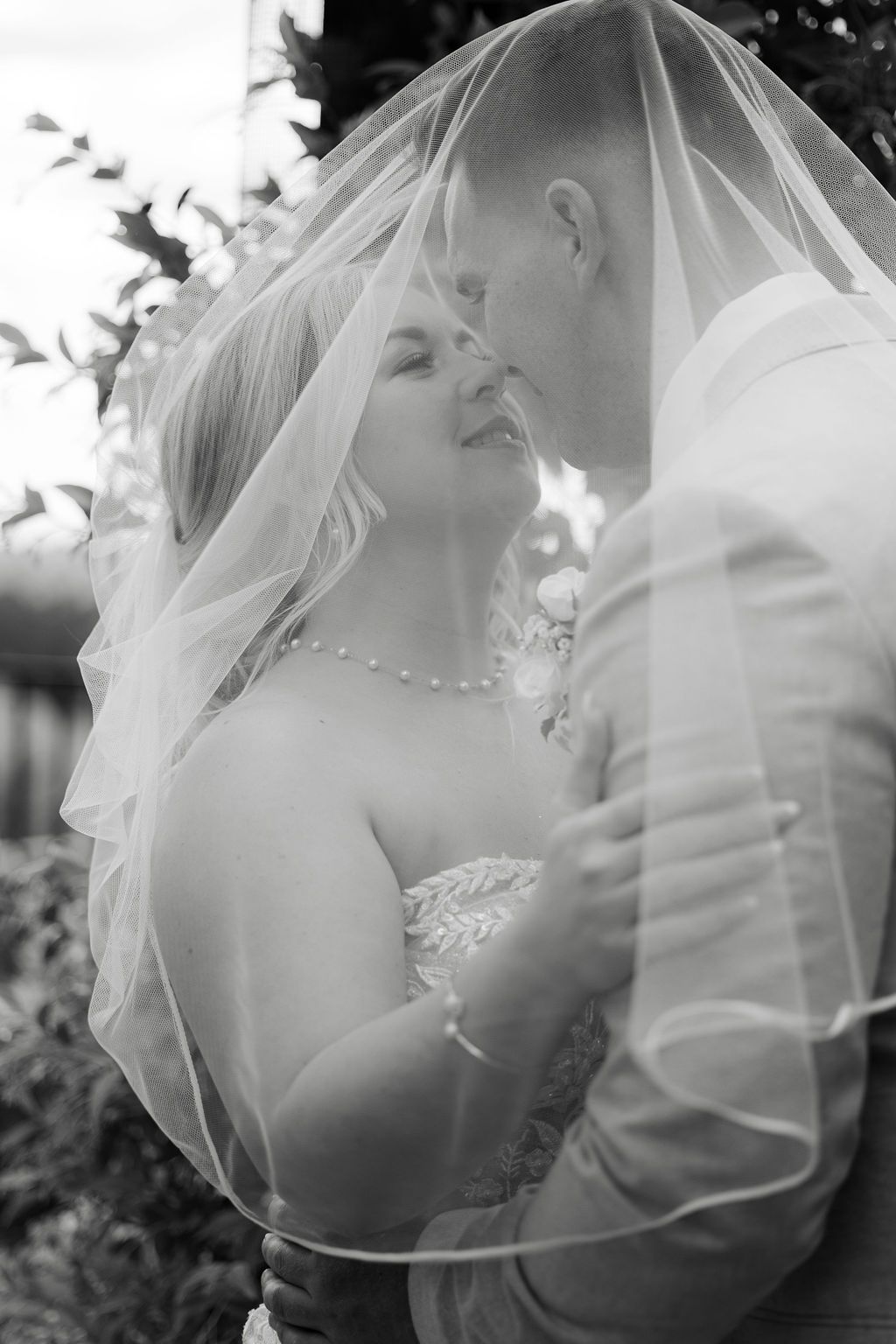 Romantic black and white wedding portraits showing intimate moments through delicate veil details.