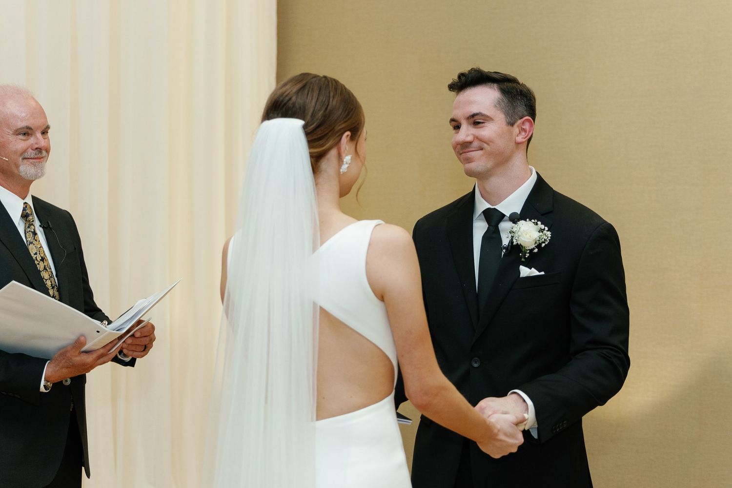 A couple stands at the altar during their wedding ceremony with an officiant reading from a book.