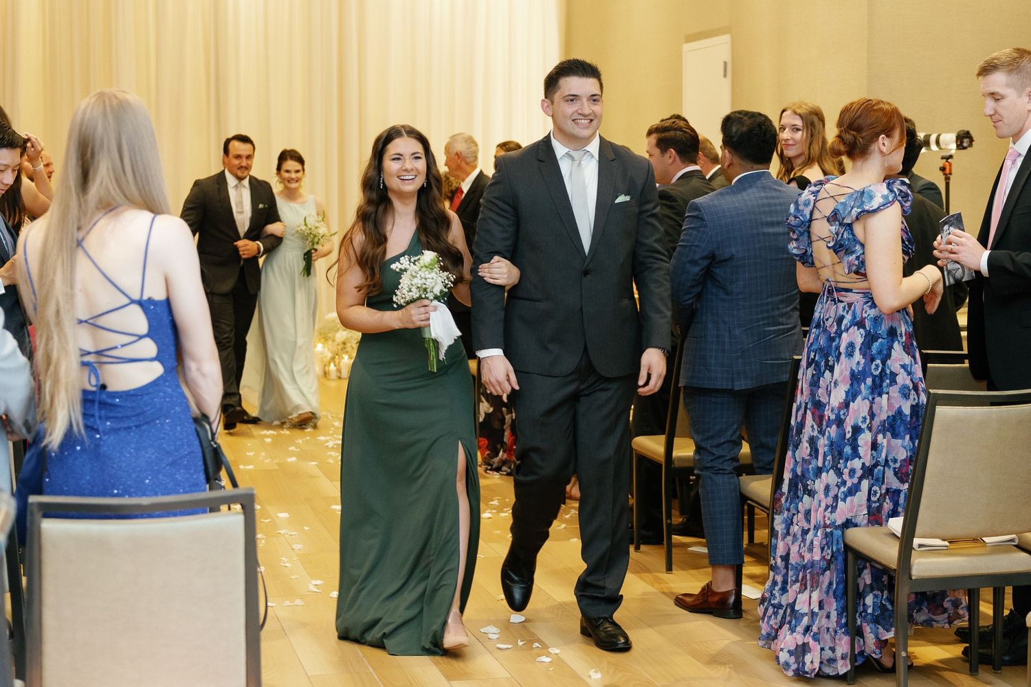 Wedding guests in formal attire mingle and socialize during a reception in an elegant indoor venue.