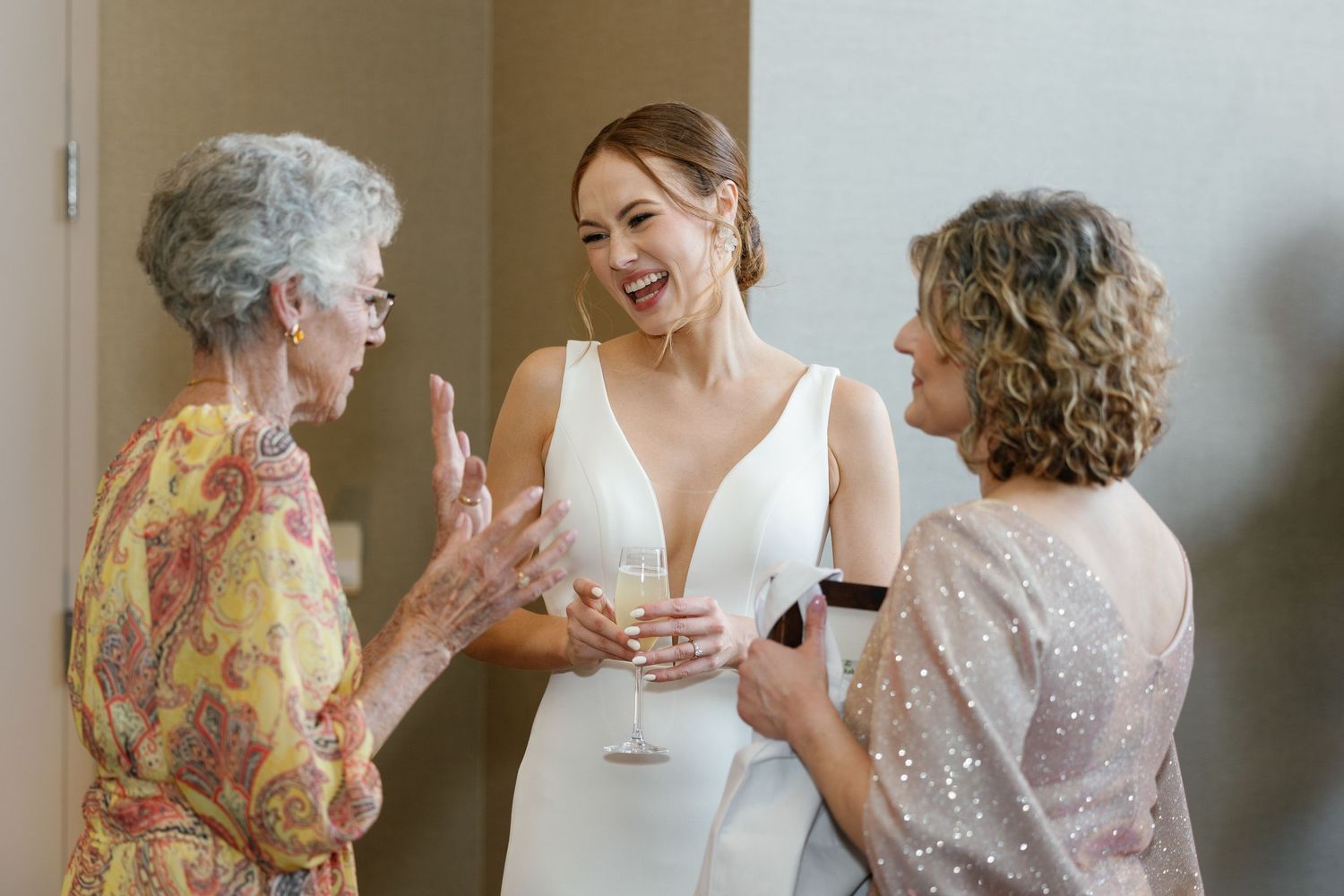 Three generations of women share a joyful moment together while celebrating in formal attire.
