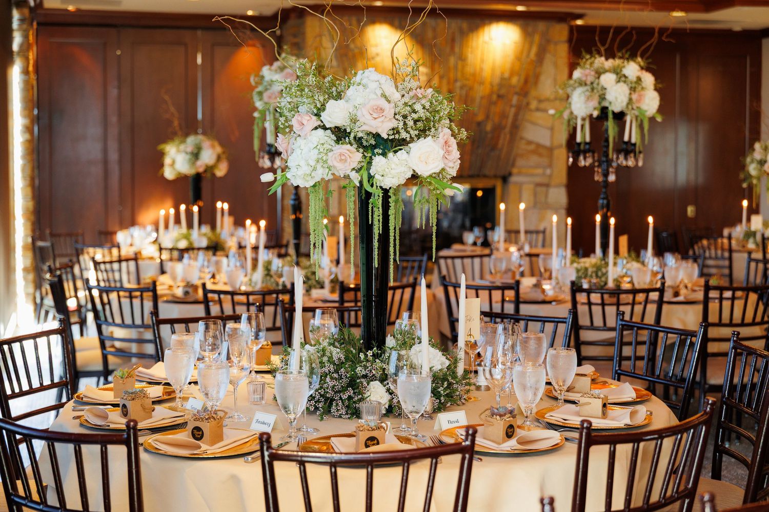 Elegant wedding reception venue with round tables, floral centerpieces and warm lighting creating a romantic atmosphere.