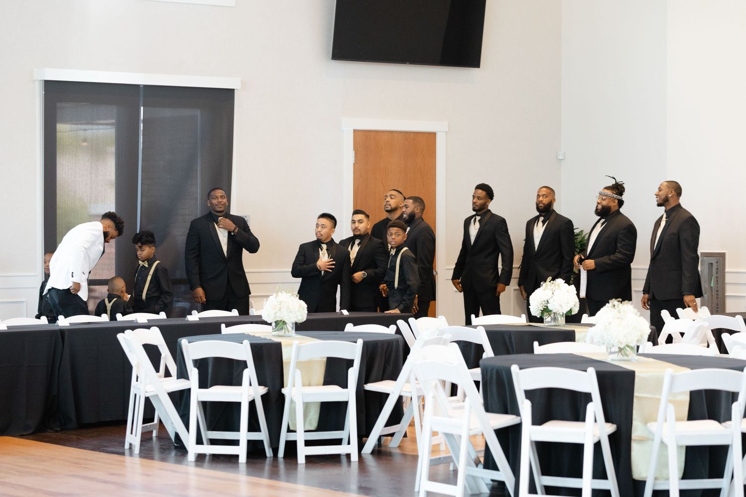 People seated at round tables in a bright white room during a formal event or conference.