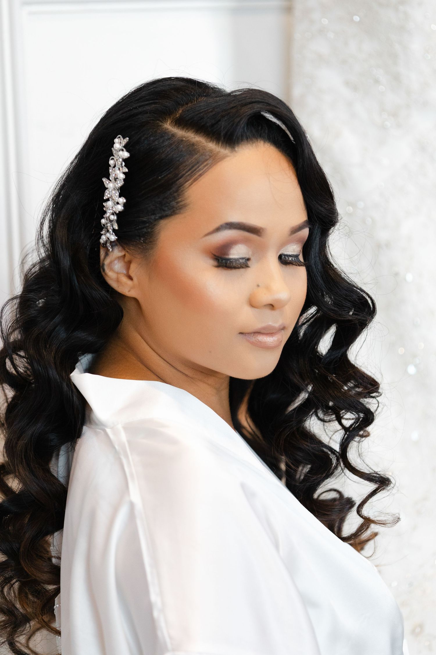 Side profile views of a bridal hairstyle with dark curls and delicate hair accessories against a light background.