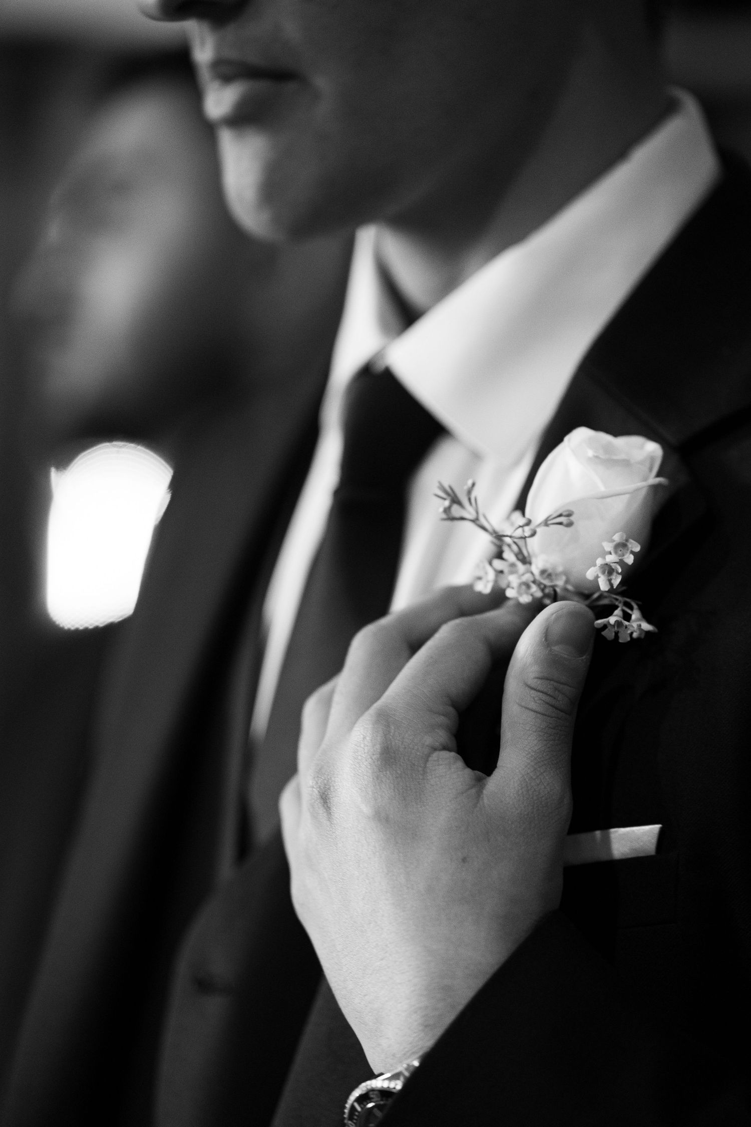 Black and white closeup of groomsmen wearing formal suits with white boutonnieres pinned to their lapels.