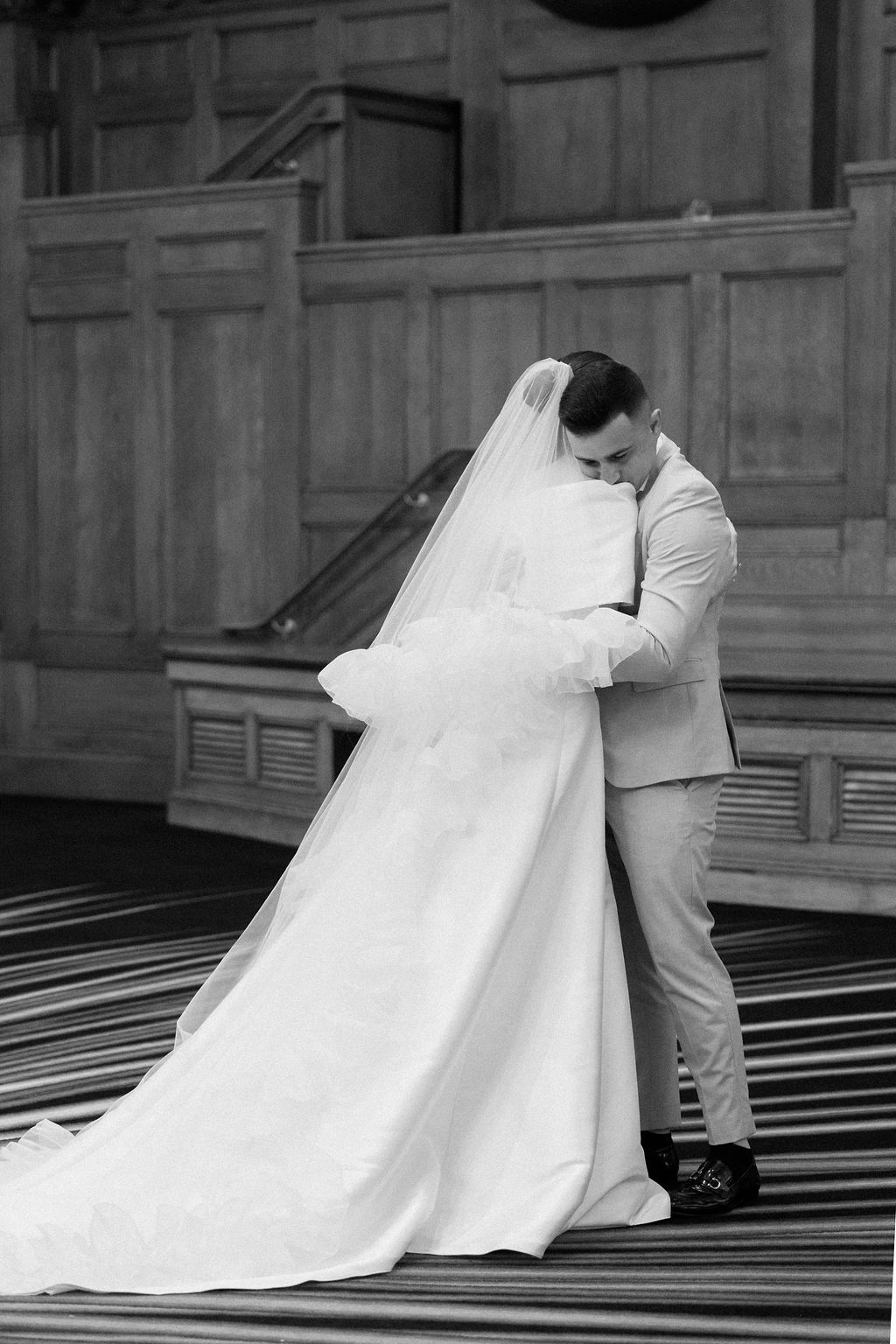 A sequence of black and white wedding photos showing a couple on grand stairs in an elegant building.