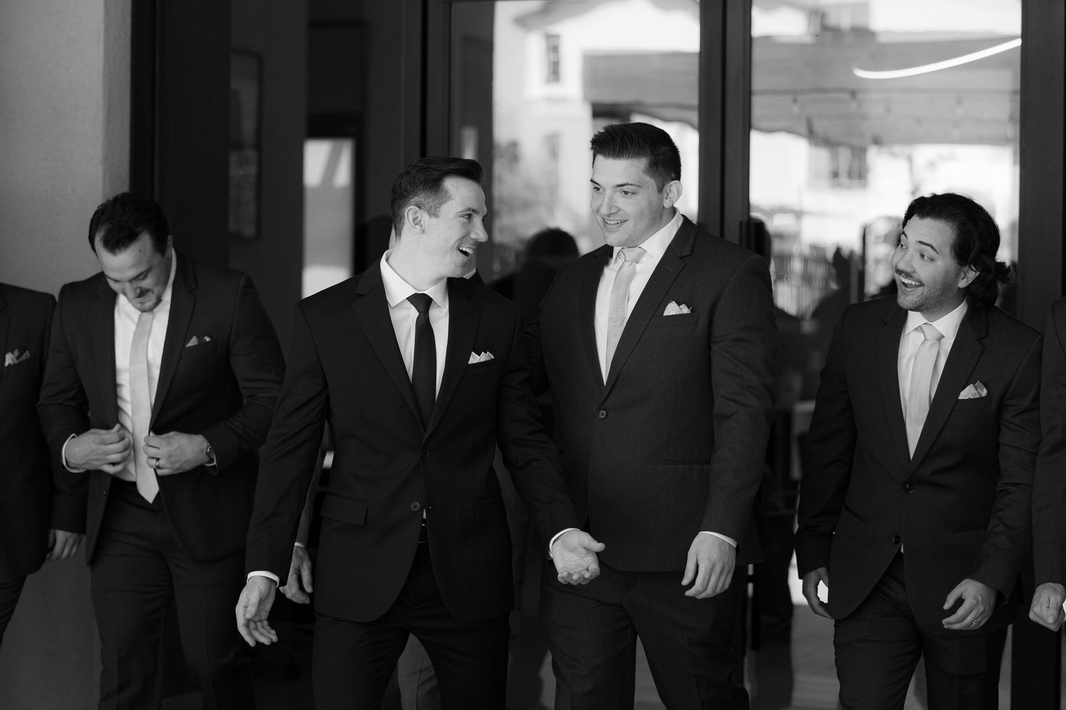 A black and white collage strip showing several men in formal suits and ties at what appears to be a business event.