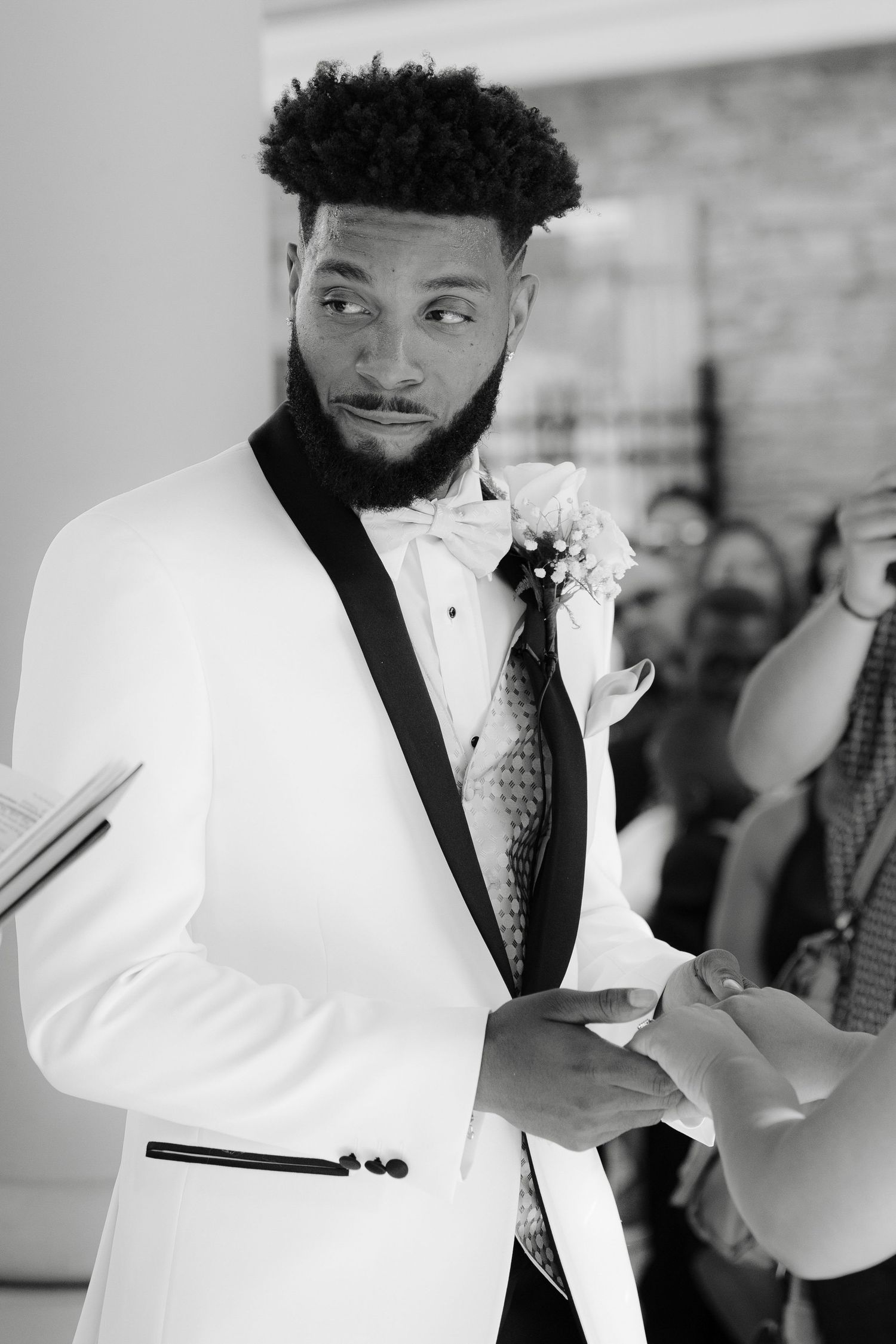 A person wearing a white tuxedo jacket and polka dot tie poses in a series of dynamic black and white portraits.