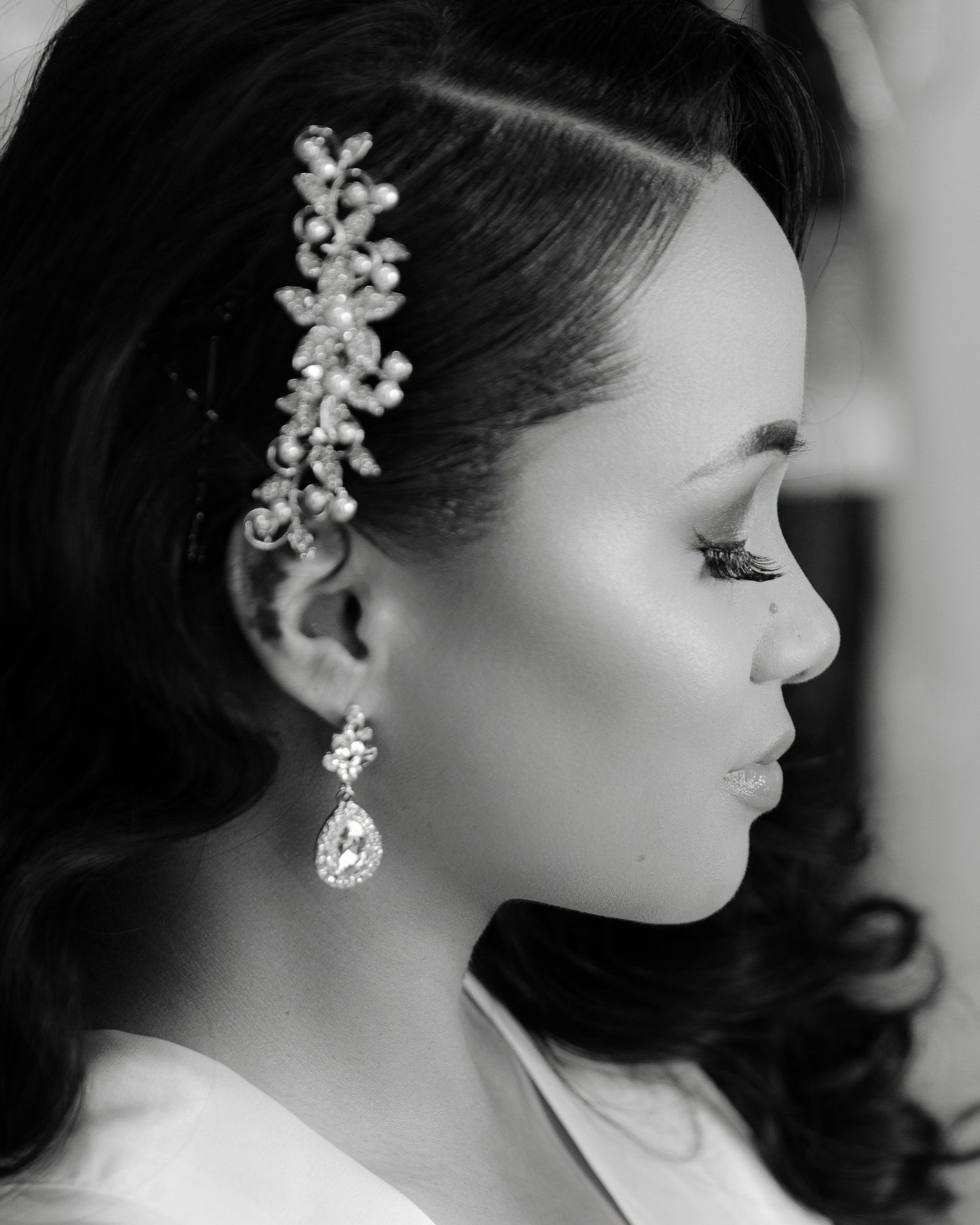 Black and white profile portrait showing elegant bridal jewelry with crystal hair accessory and teardrop earring.