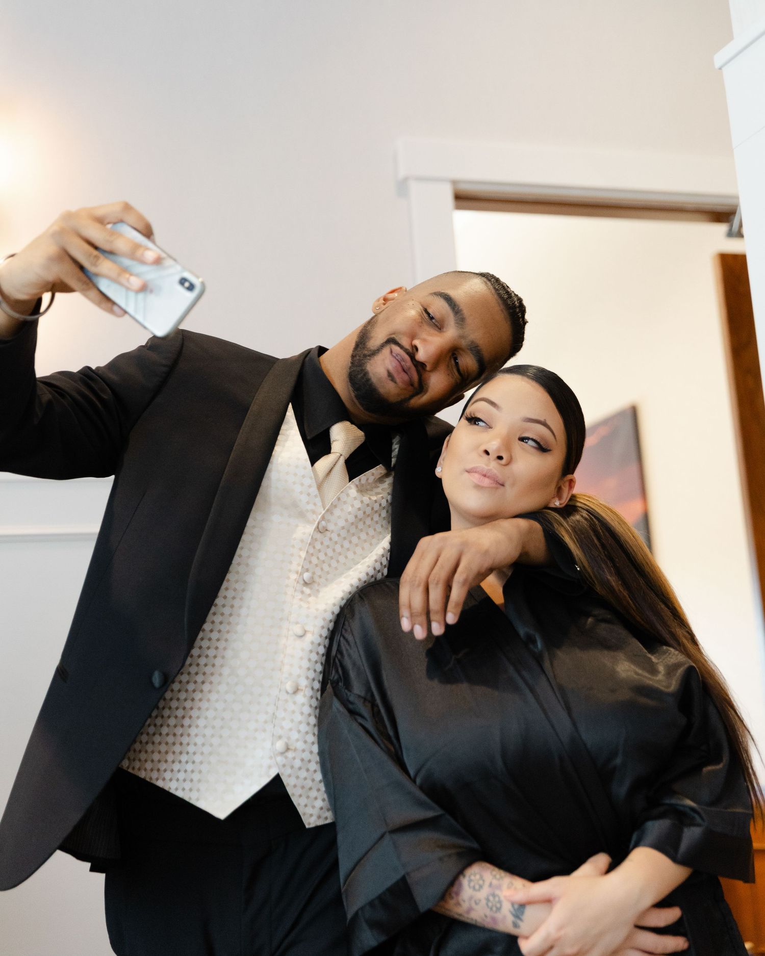 Professional couple in formal business attire sharing playful and intimate moments in a bright office setting.