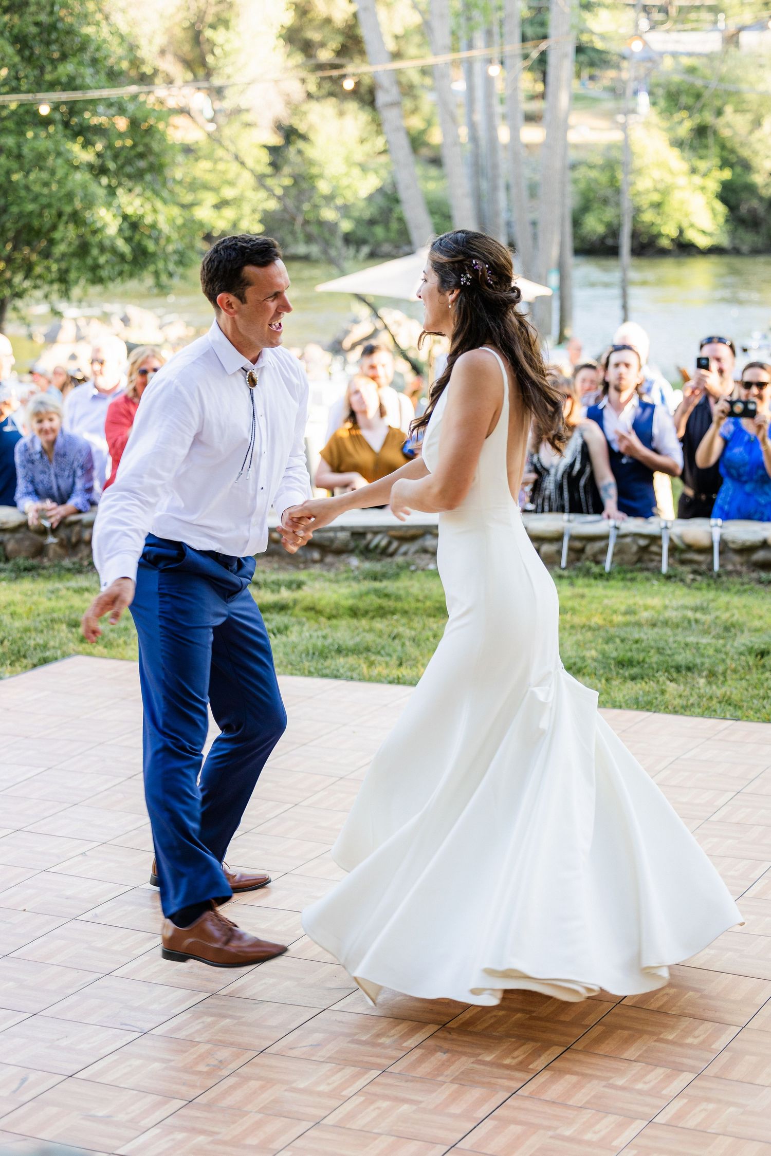 Couple performs a fun dip dance move sequence on an outdoor patio during their wedding reception celebration.