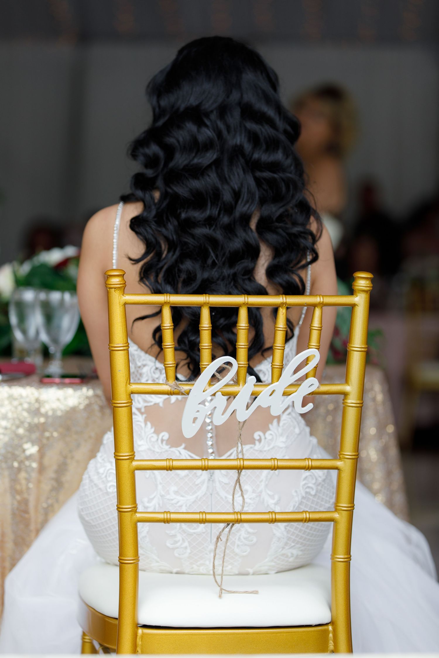 Gold Chiavari chairs with white calligraphy signs at an elegant wedding reception setup.