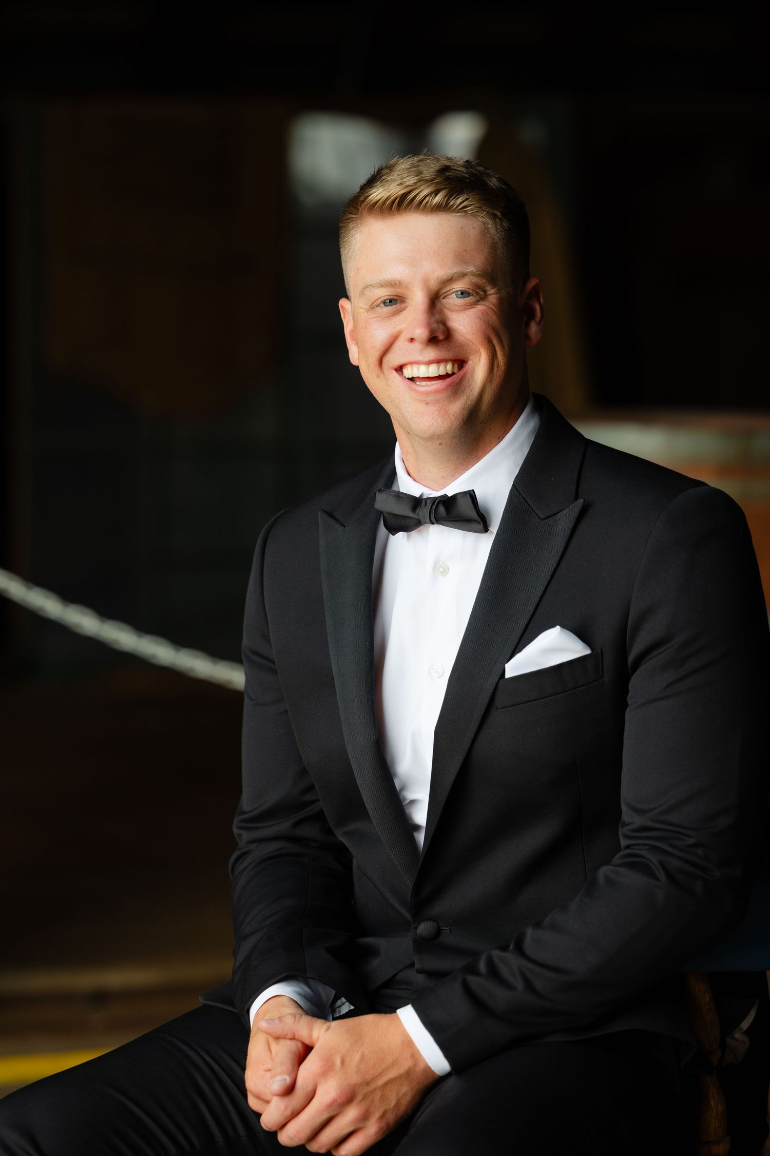 Professional portrait series showing someone in a classic black tuxedo and white dress shirt in various poses against dark background.