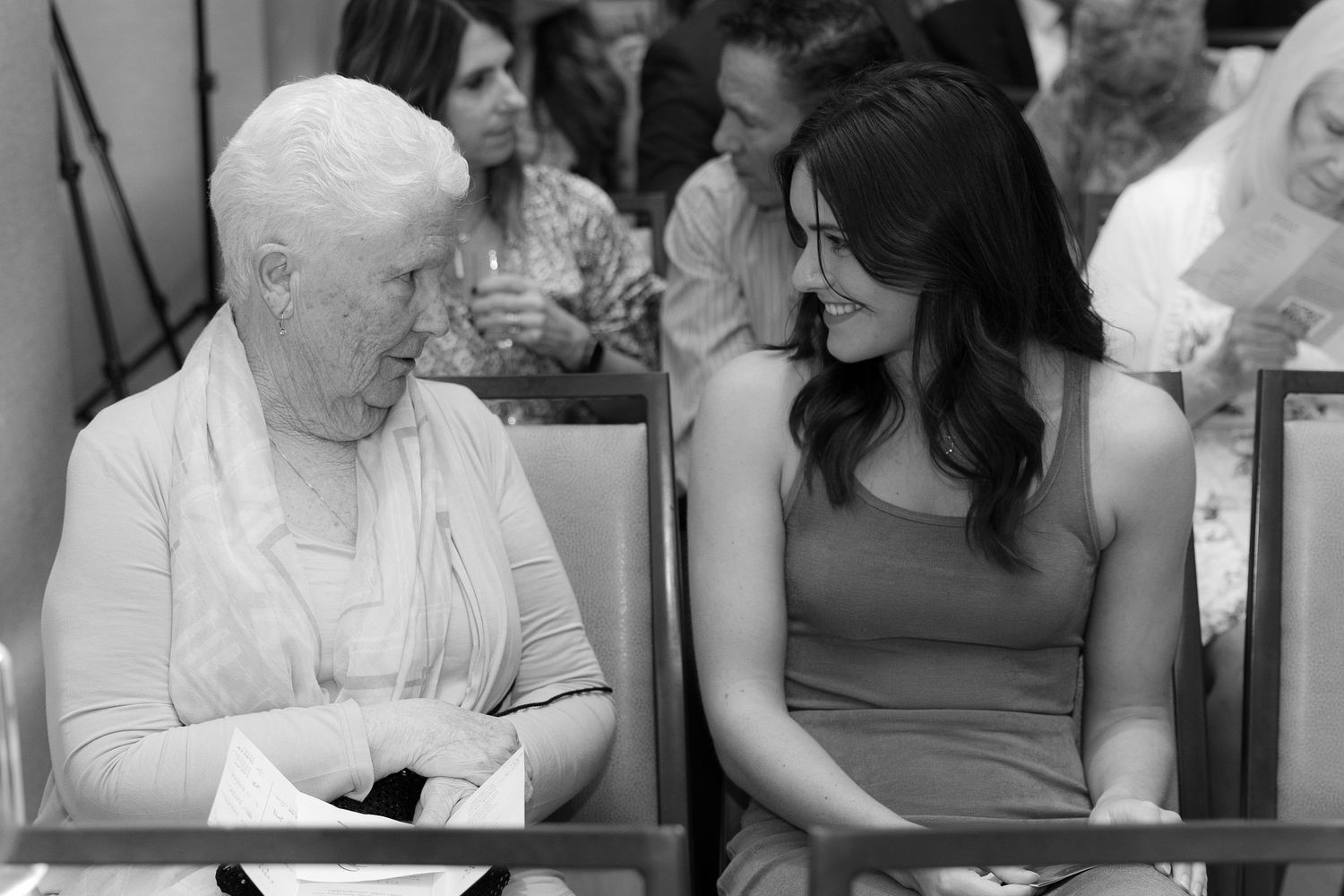 Black and white photo collage showing tender moments between elderly and younger people at what appears to be a care facility.