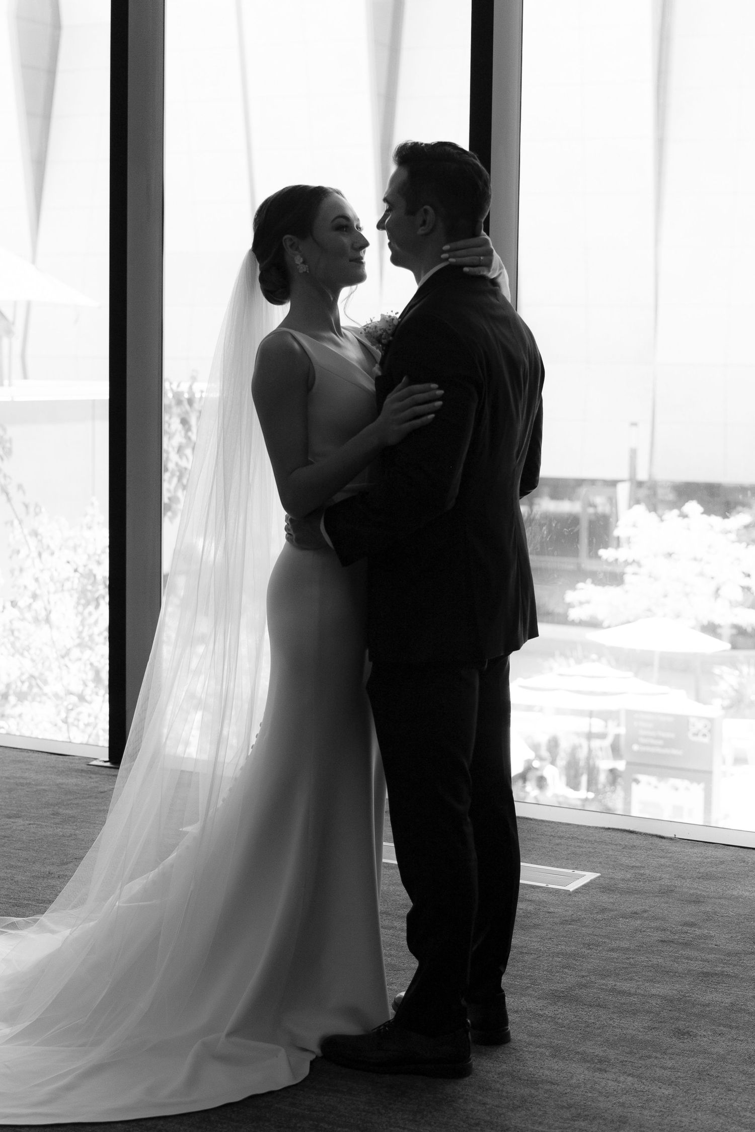 A series of silhouettes show a couple in wedding attire sharing intimate moments against bright white curtains.
