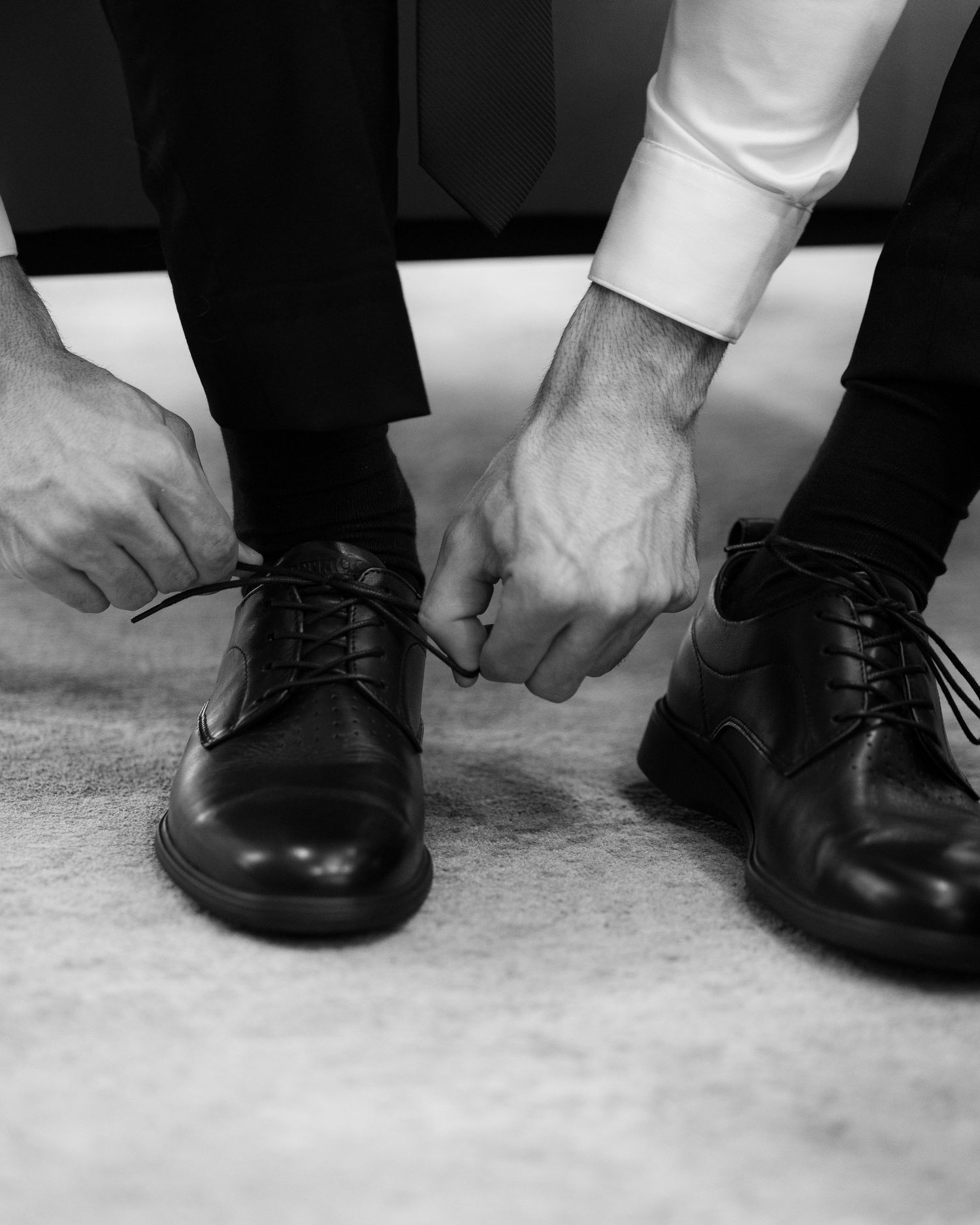 A sequence of black and white photos showing dress shoes and hands tying formal shoelaces on carpet.