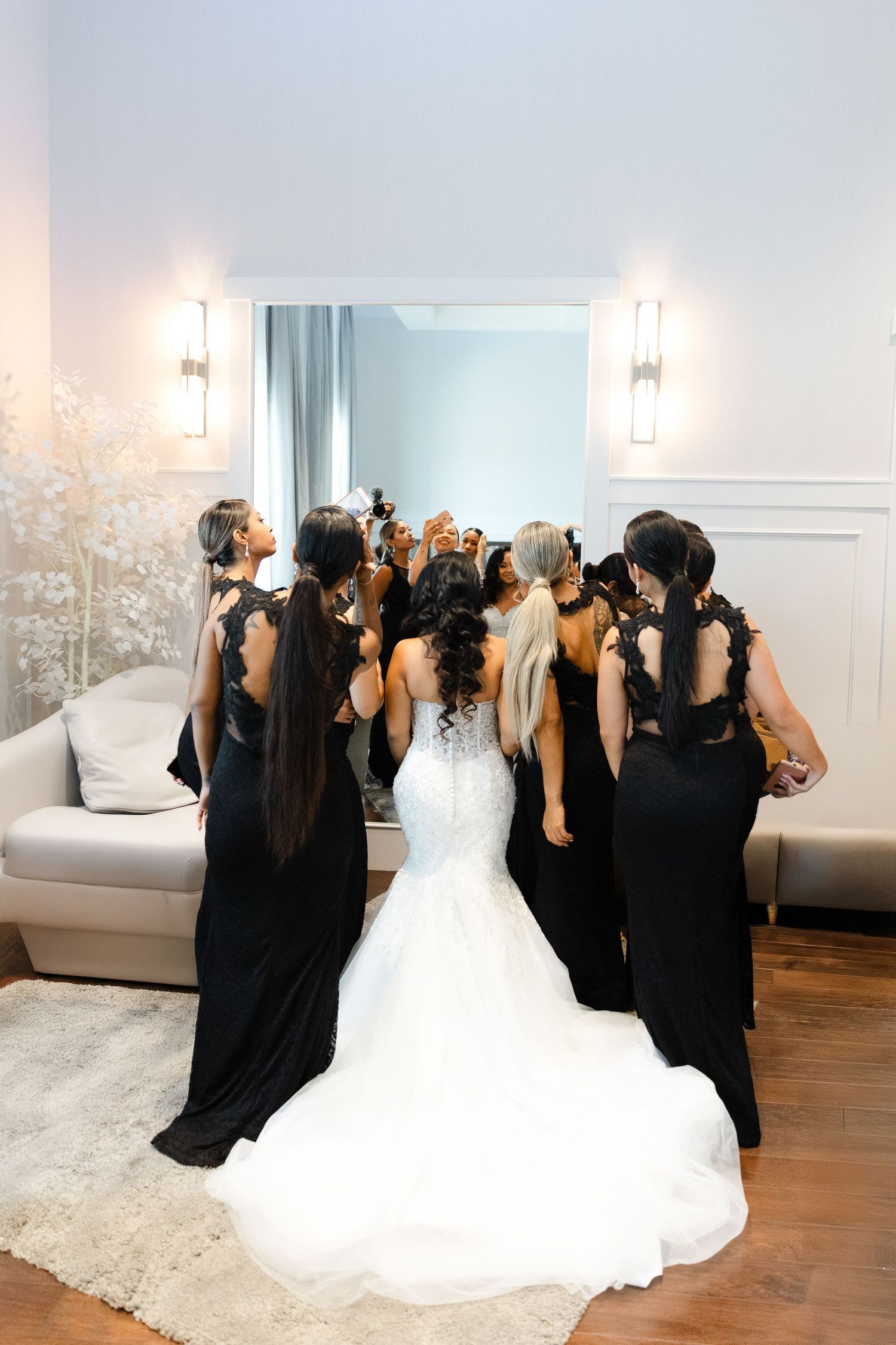 A bride in a white gown and bridesmaids in black dresses pose together in a sequence of candid wedding photos.