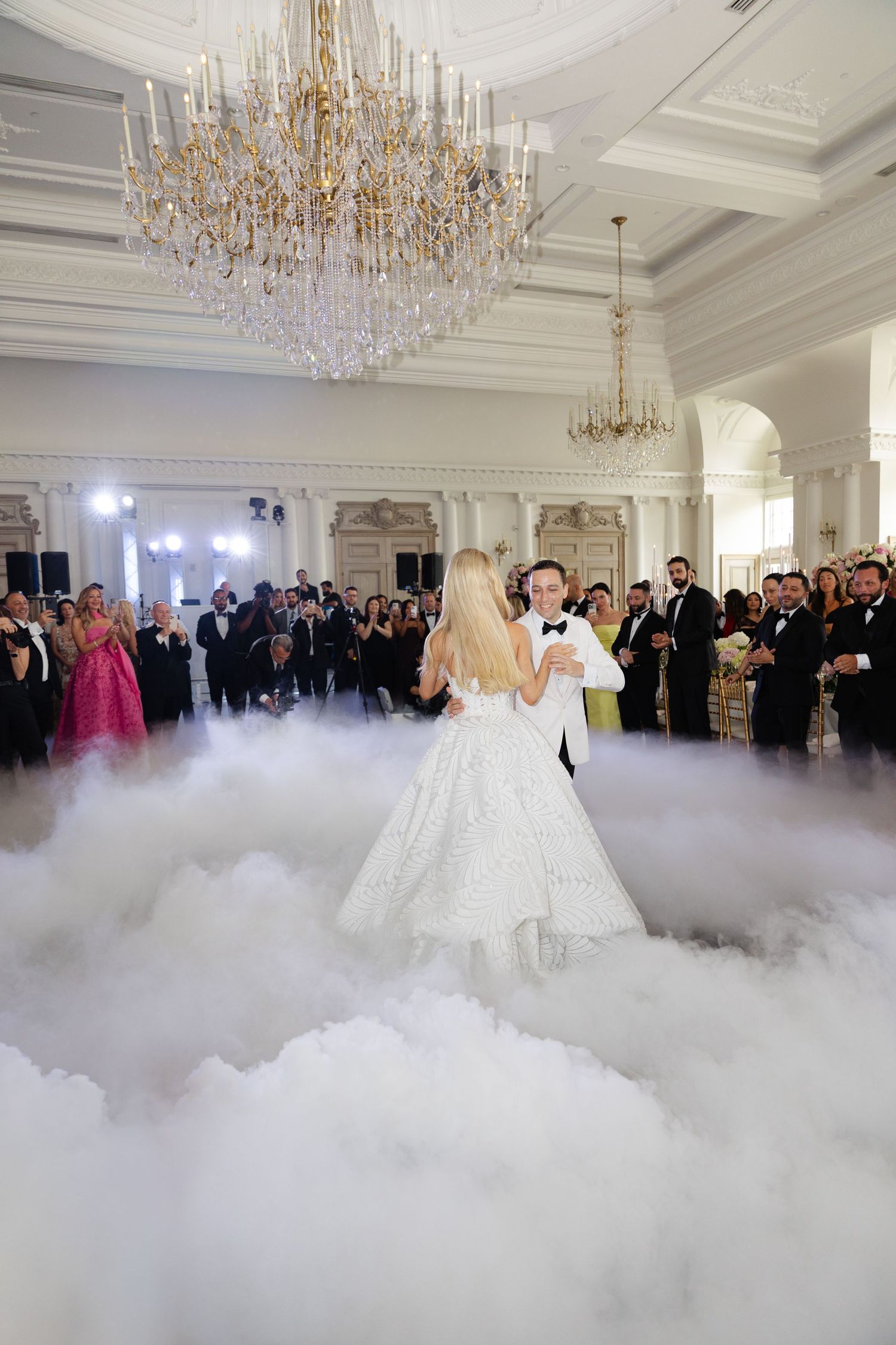 Elegant ballroom filled with low-lying fog and crystal chandeliers during a wedding reception.