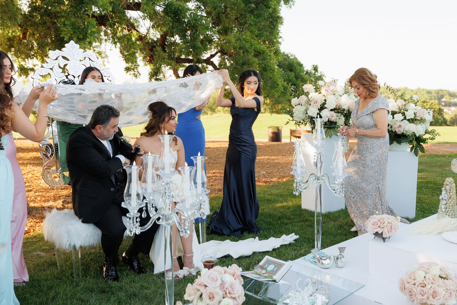 Wedding guests celebrate and raise their glasses during an elegant outdoor reception at golden hour.