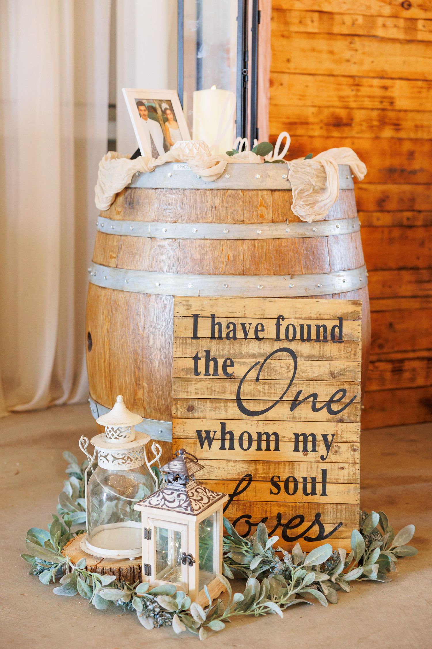 Rustic wooden card box with cursive text and eucalyptus greenery displayed at a wedding reception.