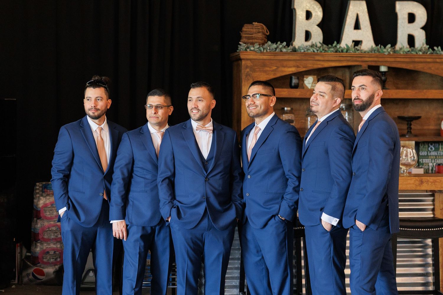 Groomsmen in matching navy blue suits stand together in a line for a wedding photo.