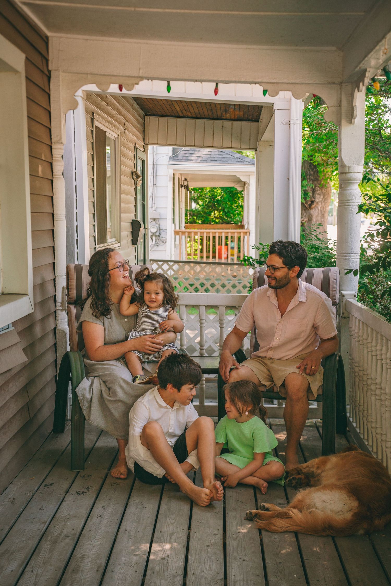 Family with young children and their dog relaxing on a front porch during a candid lifestyle family photography session in Kingston, Ontario