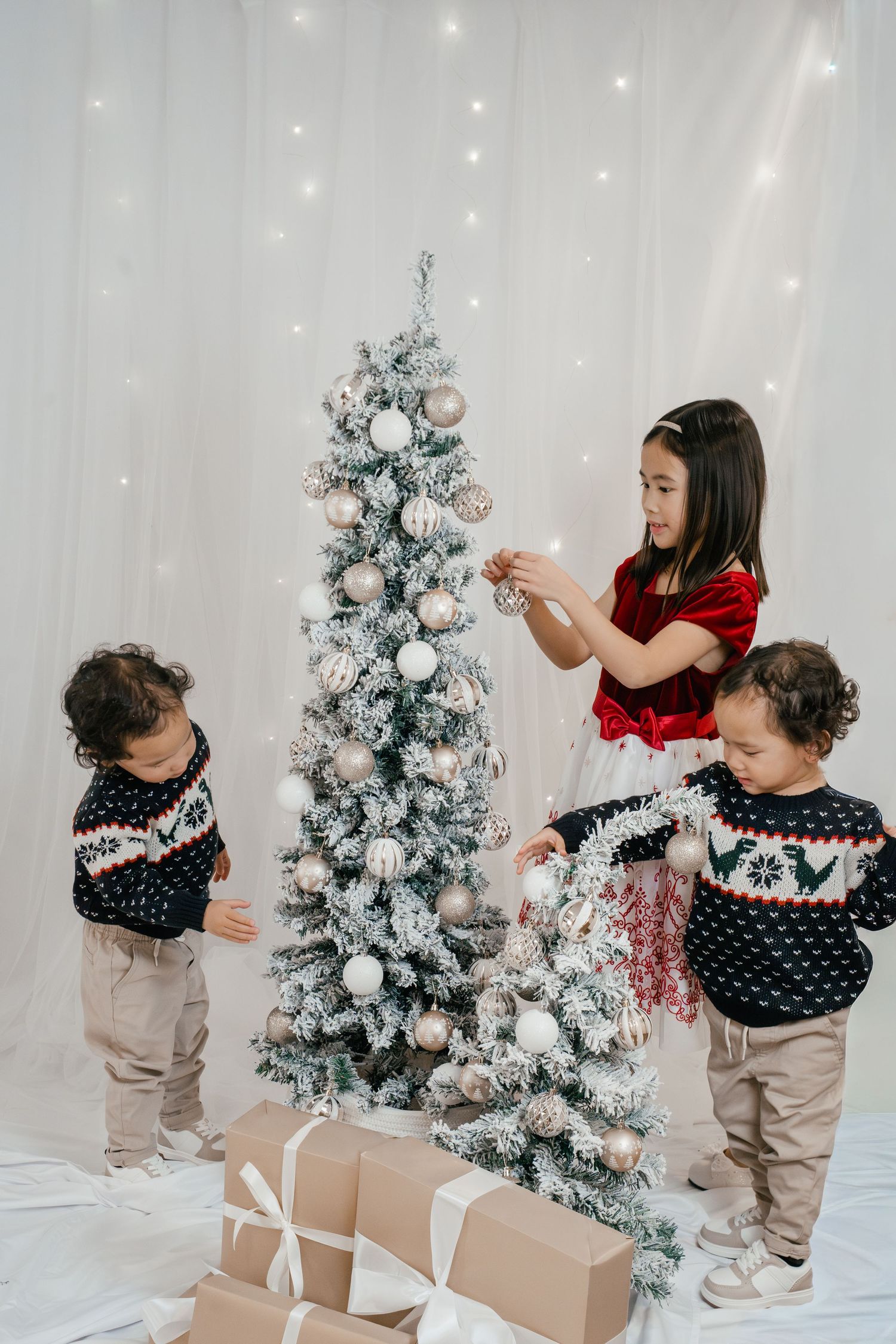 Daughter decorating a snowy Christmas tree with her brothers during a candid Christmas mini photography session in Kingston, Ontario.