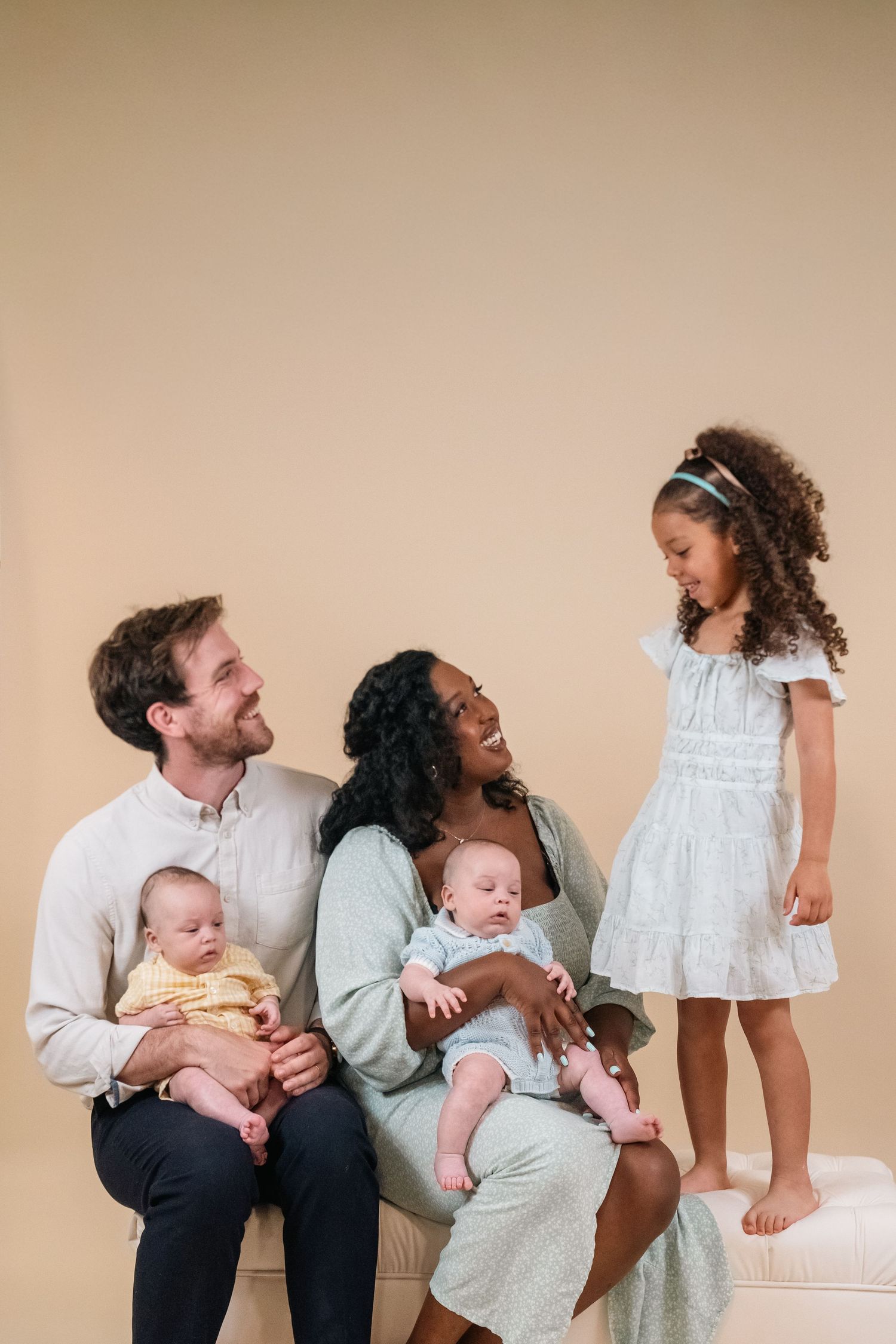 Family of five posing together against a neutral studio backdrop during an indoor family portrait photography session.