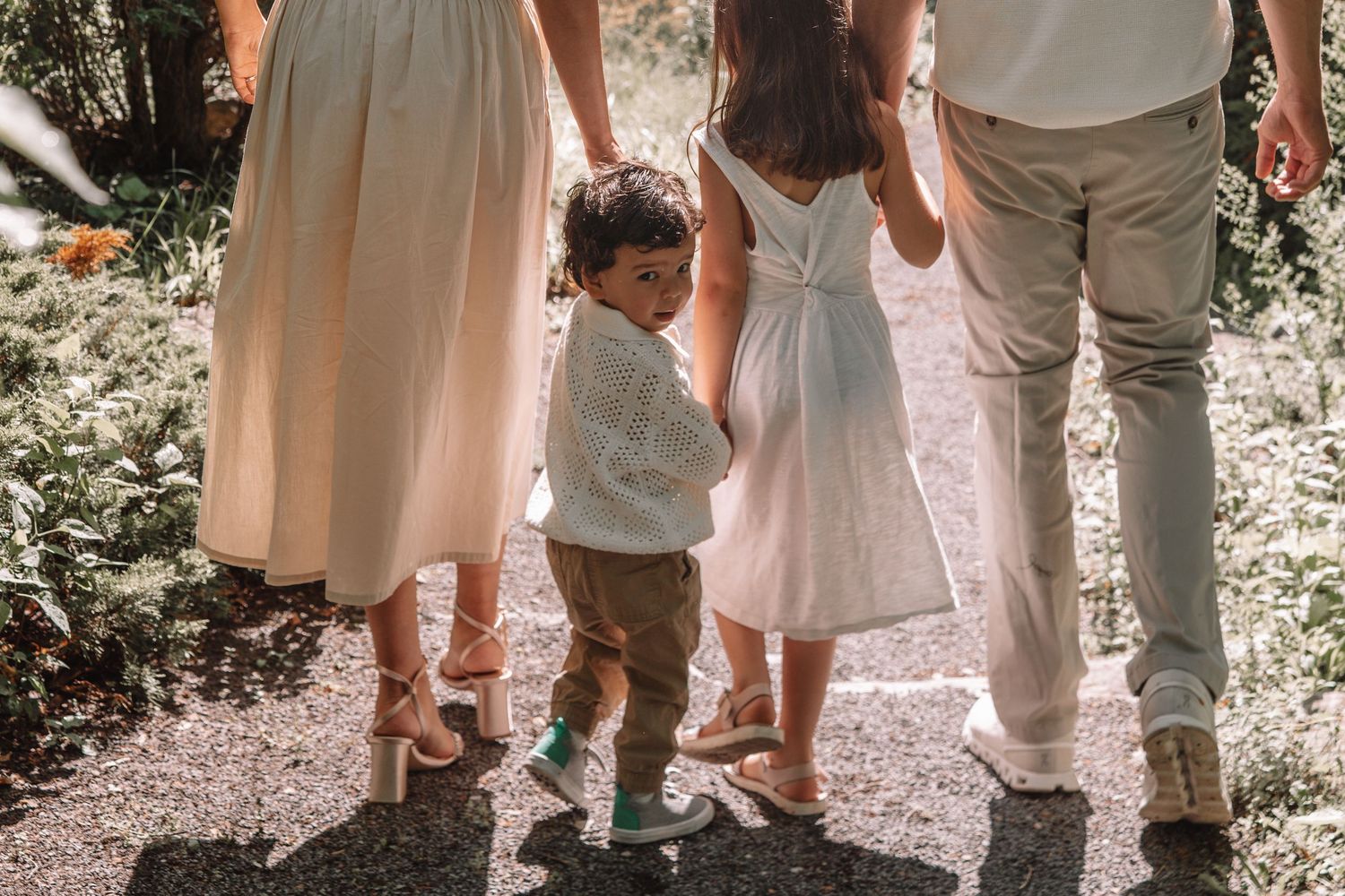 Close-up of parents walking hand in hand with their two children during an outdoor spring lifestyle family photoshoot in Kingston, Ontario.