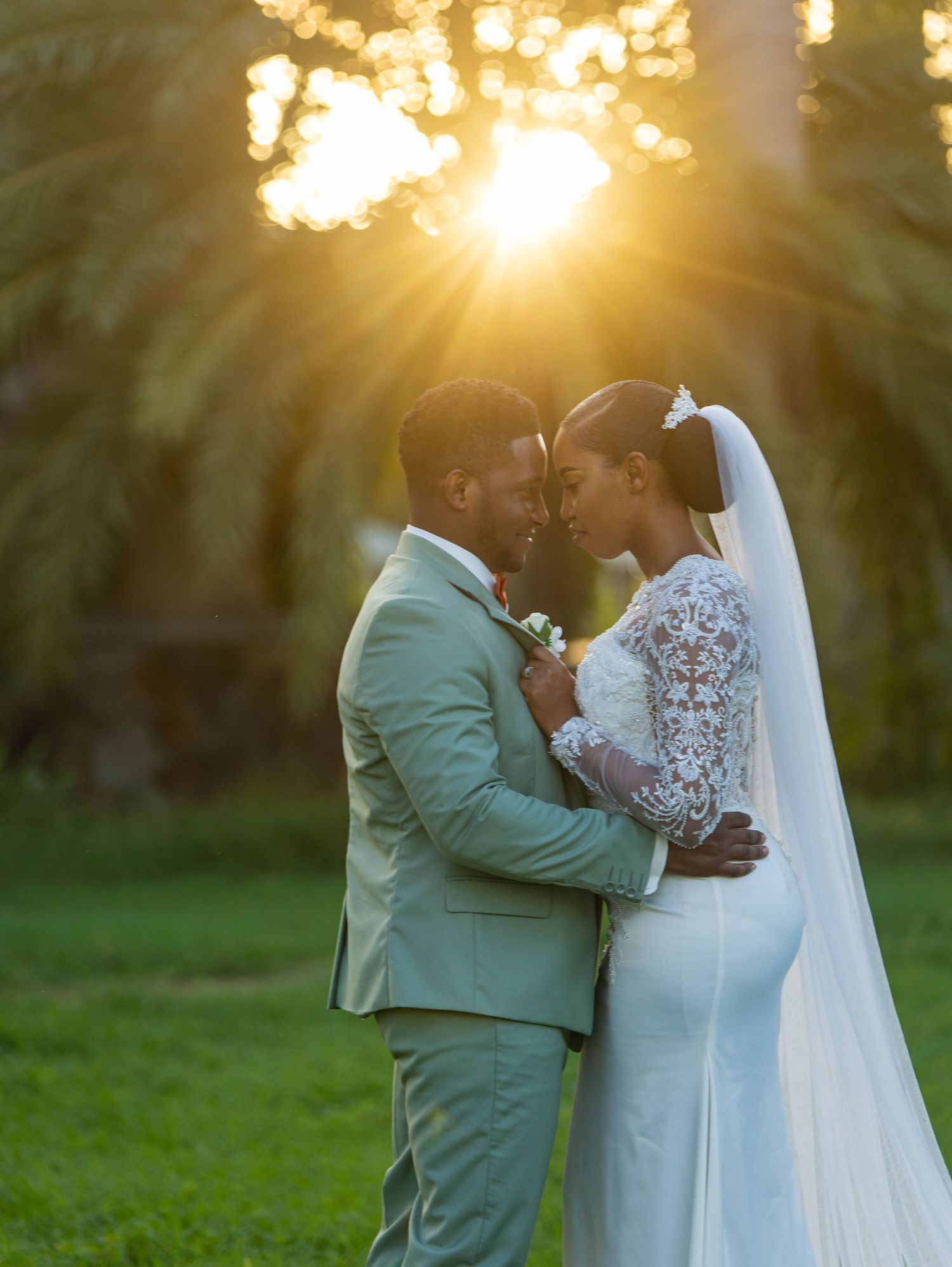 A romantic sunset wedding portrait shows a couple embracing in a garden with golden sunbeams streaming through trees.