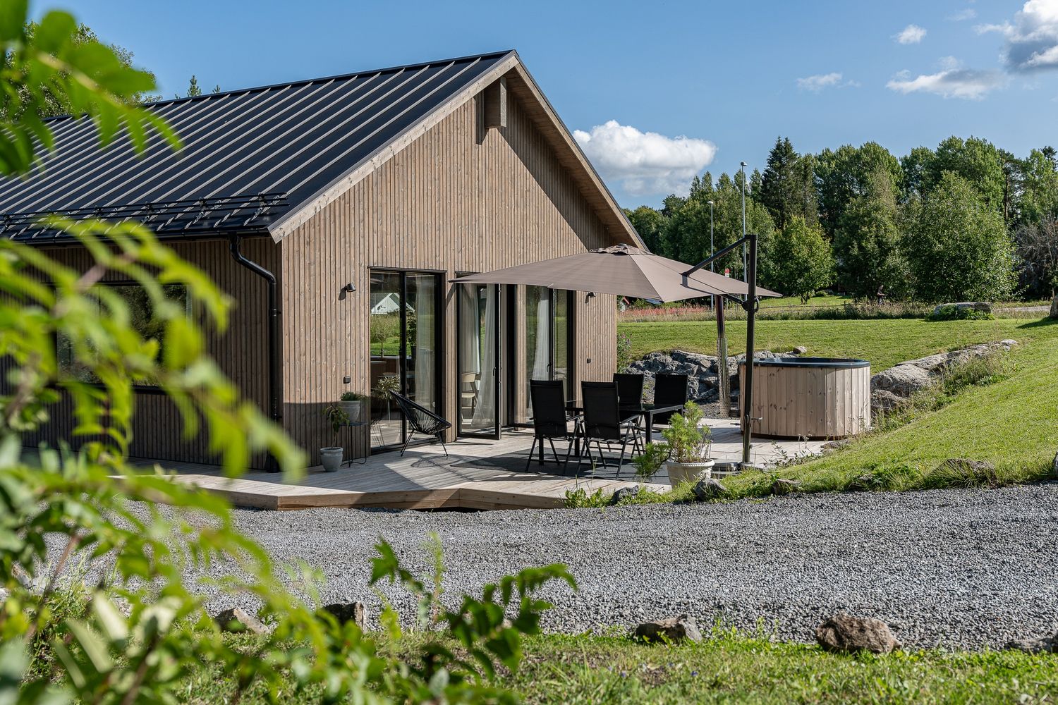 Trähus och terrass i sommargrönska