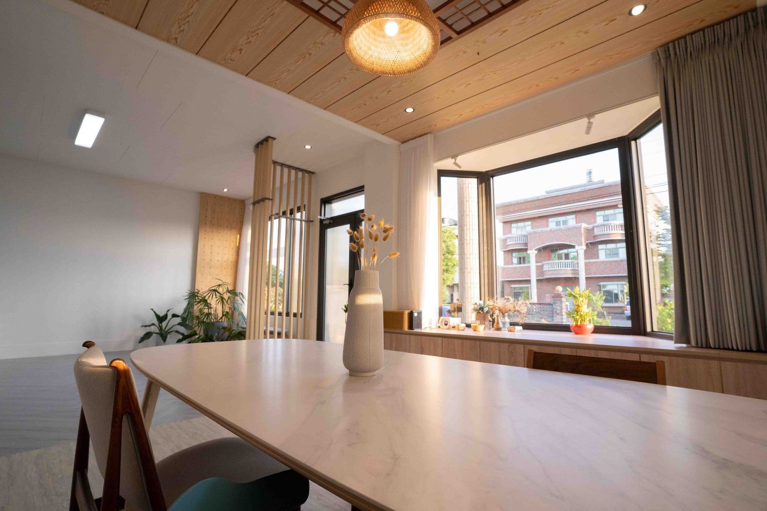 Modern apartment interior with wooden ceiling, pendant lighting, and minimalist decor showcases clean design aesthetic.