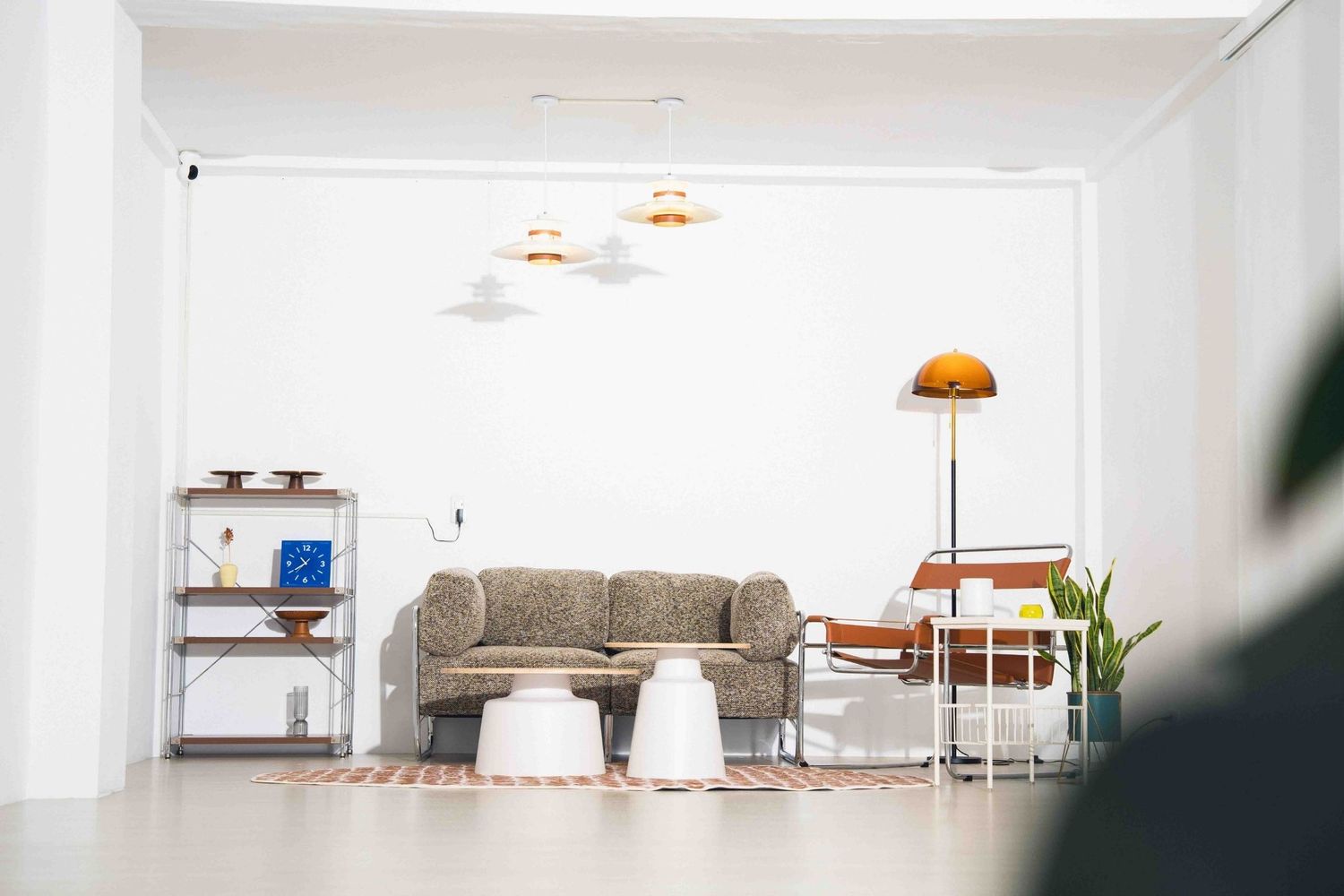 Minimalist white living room interior with gray sofa, modern pendant lights, and vintage floor lamp.