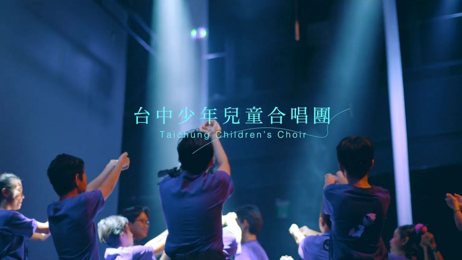 Silhouettes of performers dancing gracefully on a dark stage with blue lighting effects.