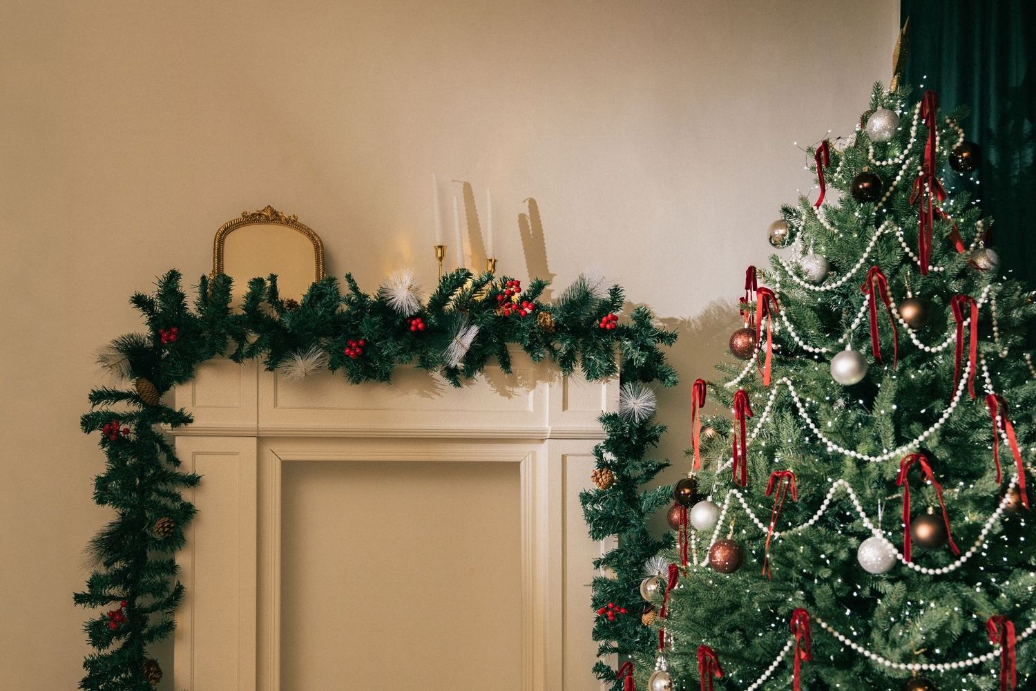 Festive living room with decorated Christmas tree, garland-draped fireplace, red ribbons, silver baubles, and lit candles.