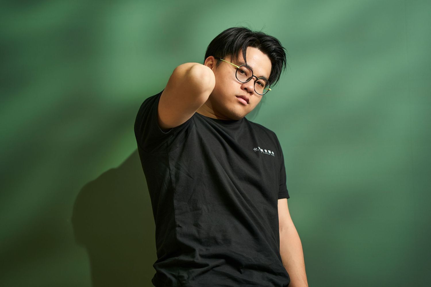 Person in black sleeveless top poses against blurred green background in artistic portrait series.
