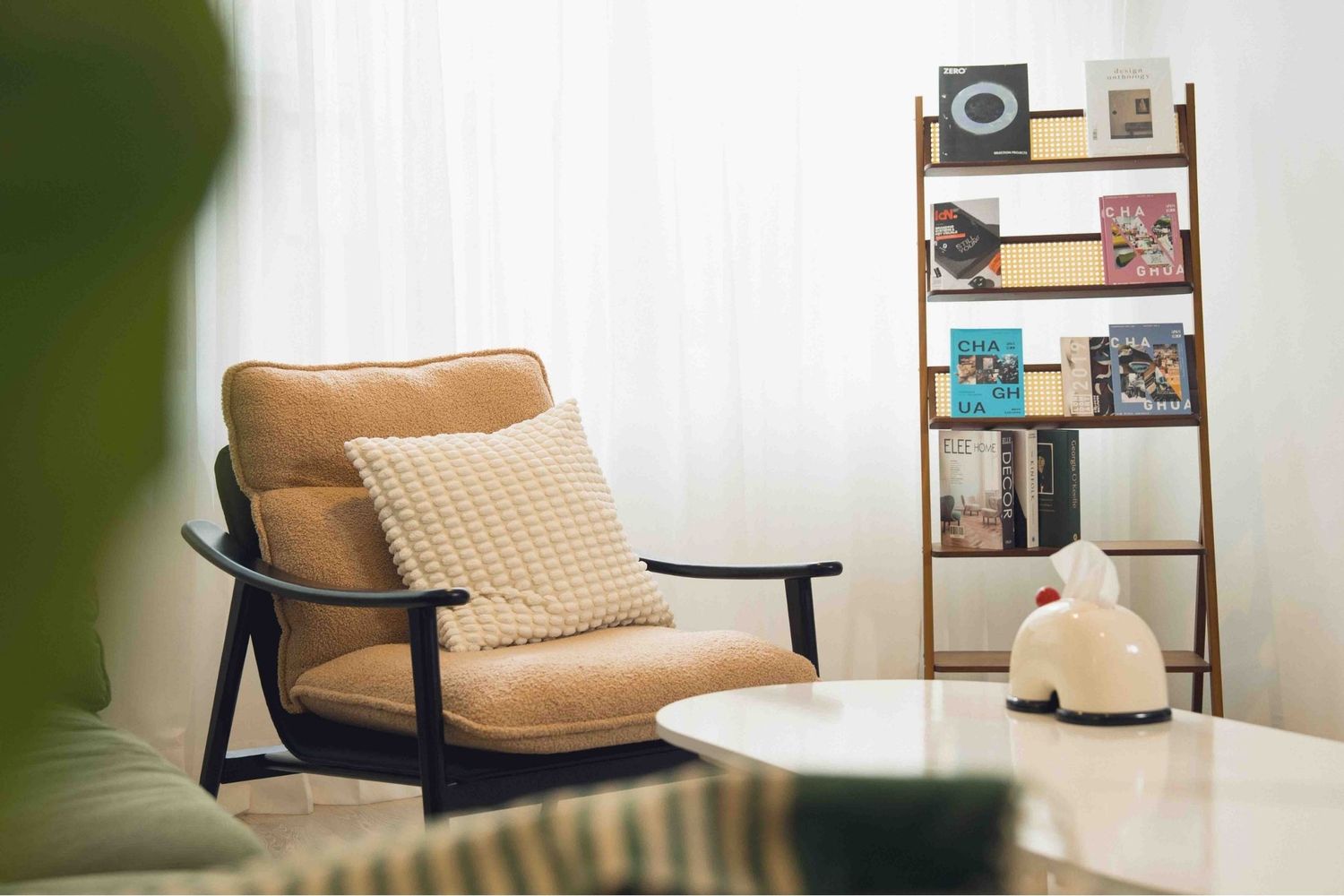 Modern tan leather armchair with quilted pattern and dark wood frame sits elegantly against a white wall.