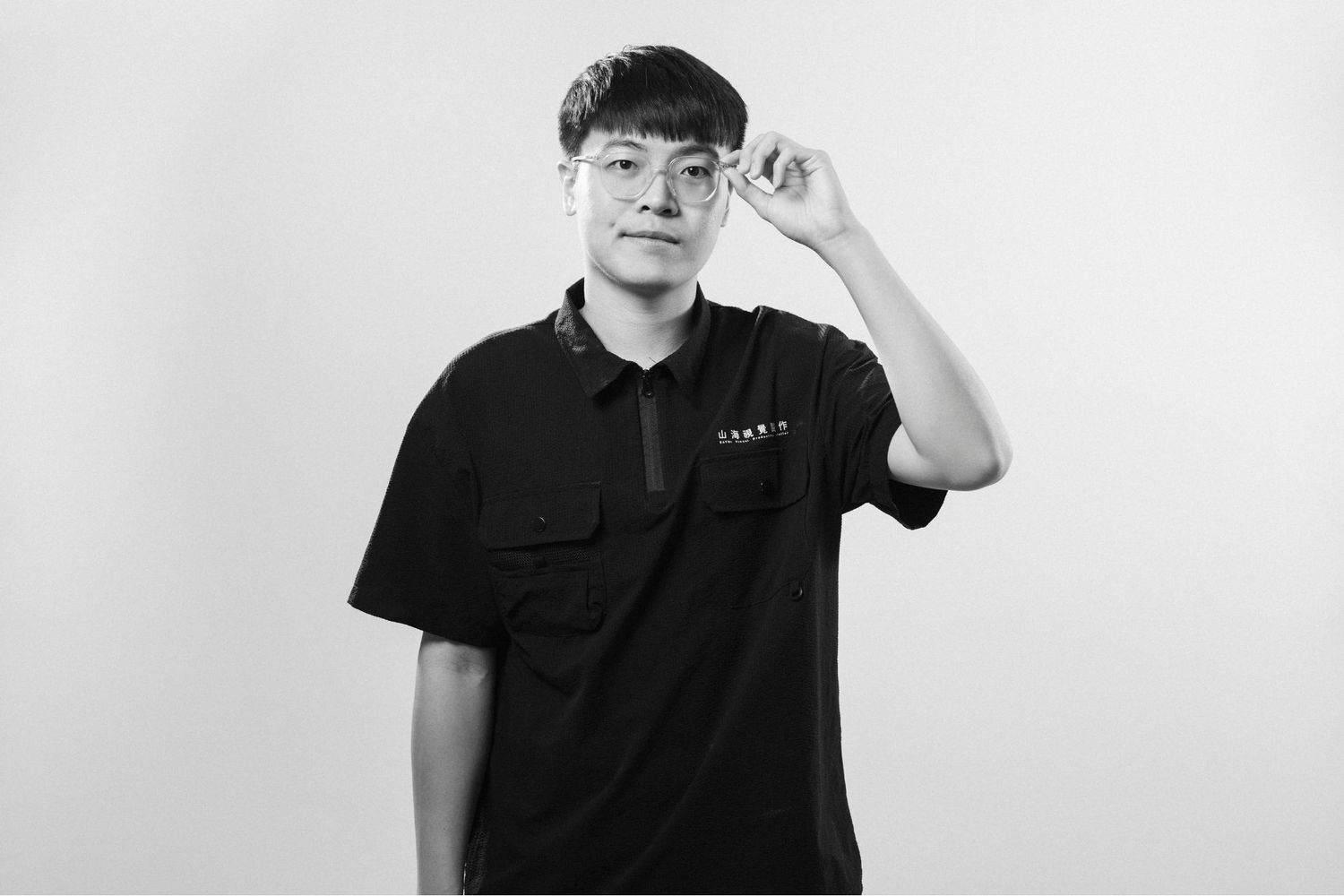 A person in a black polo shirt stands against a white background making various casual poses.