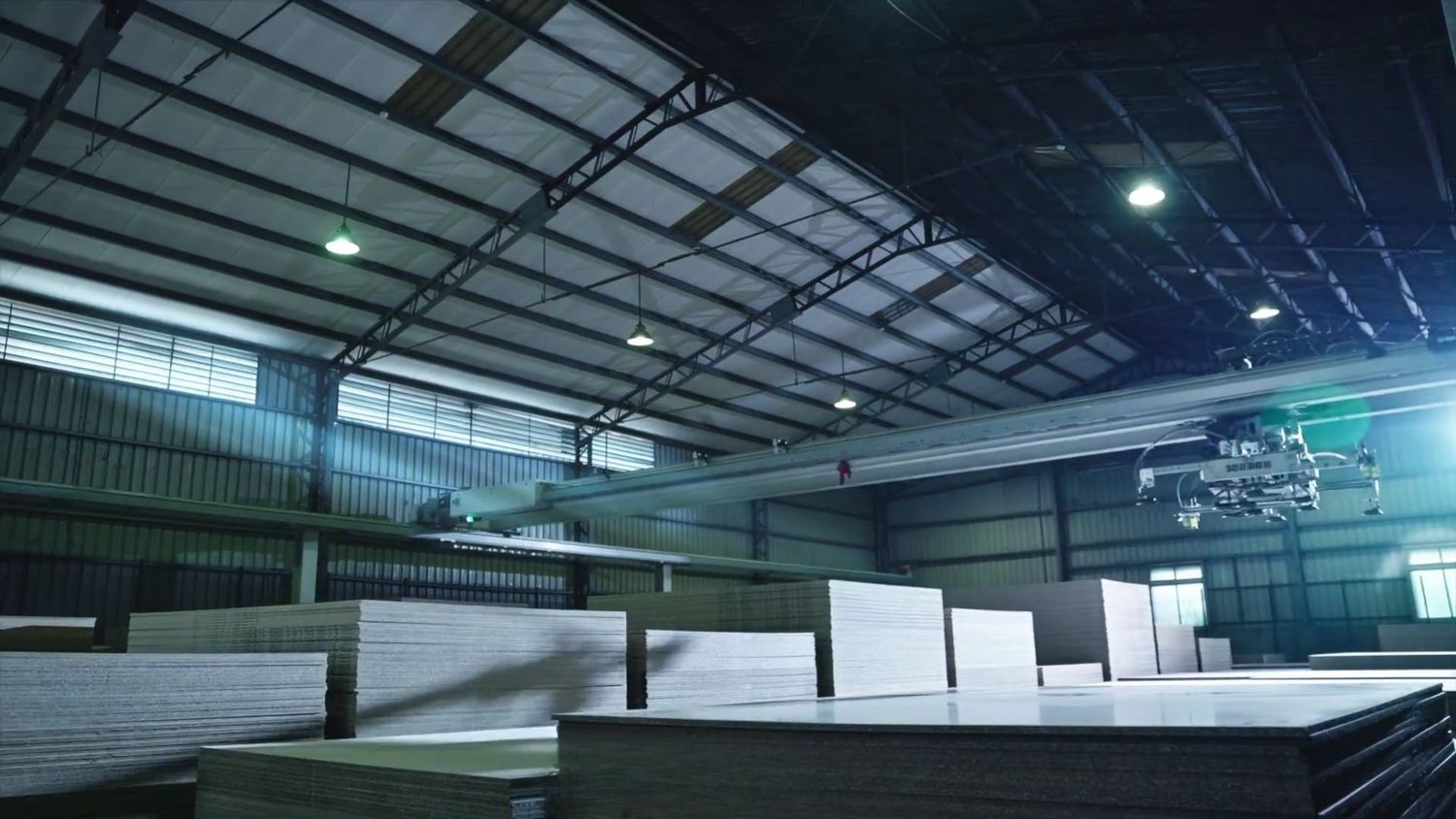 Industrial warehouse interior with metal roof structure and lighting fixtures illuminating the large open space.