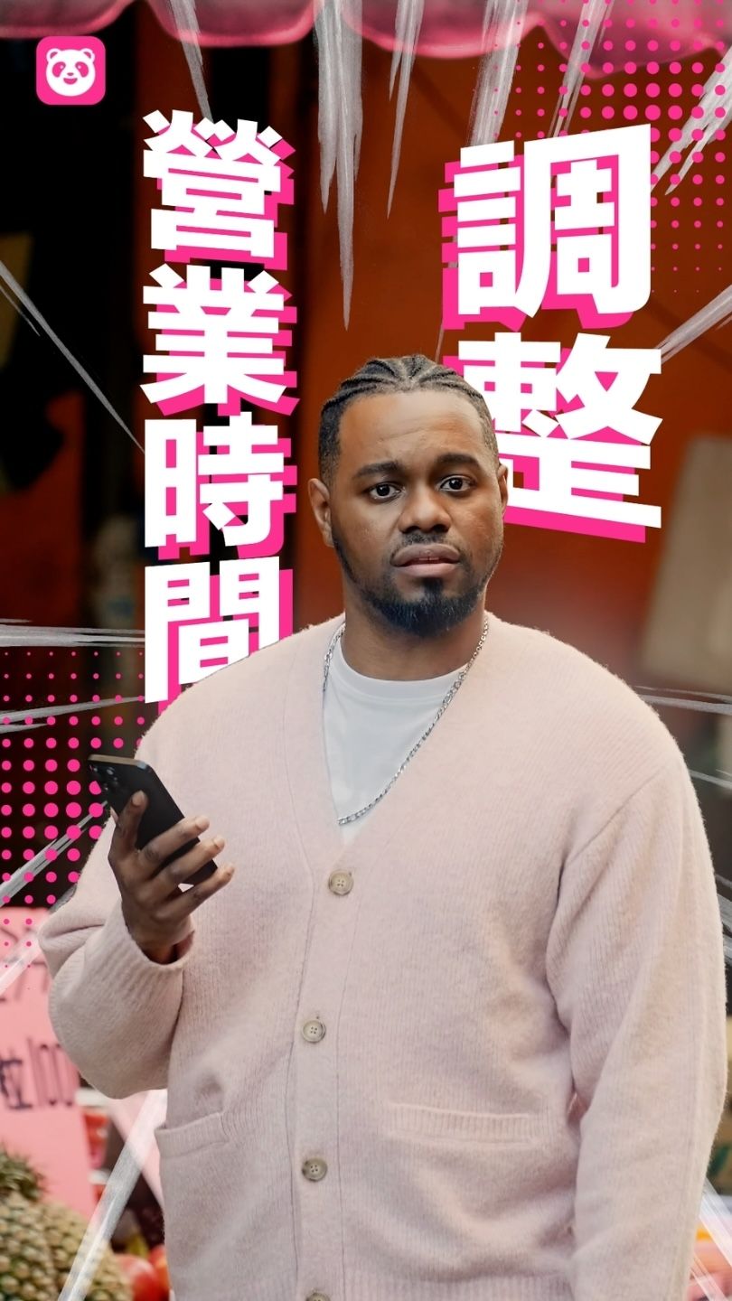 Person in beige cardigan holding smartphone stands against red background with Japanese text overlay.