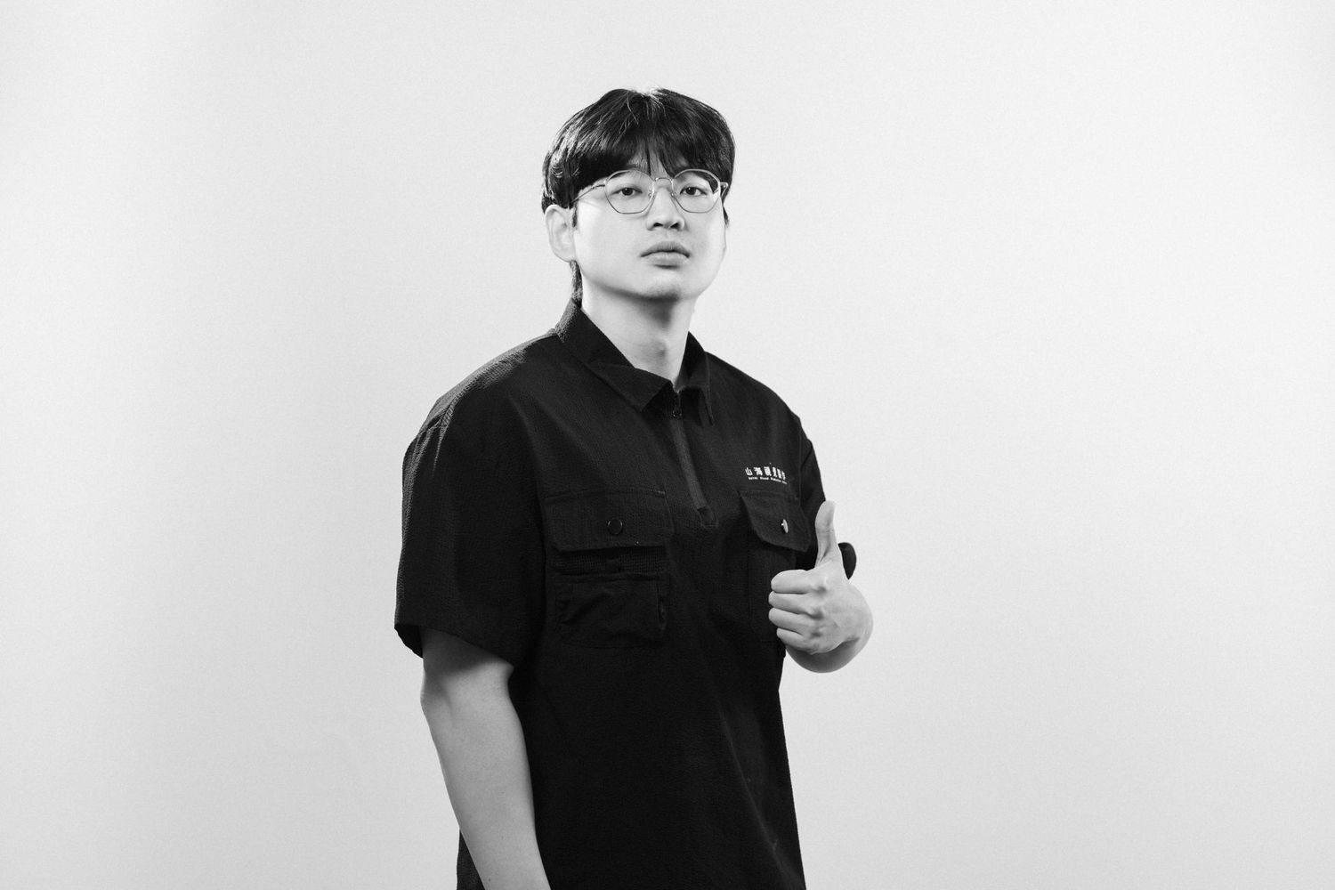 A person in a black t-shirt and face mask poses against a white background in a minimalist style.