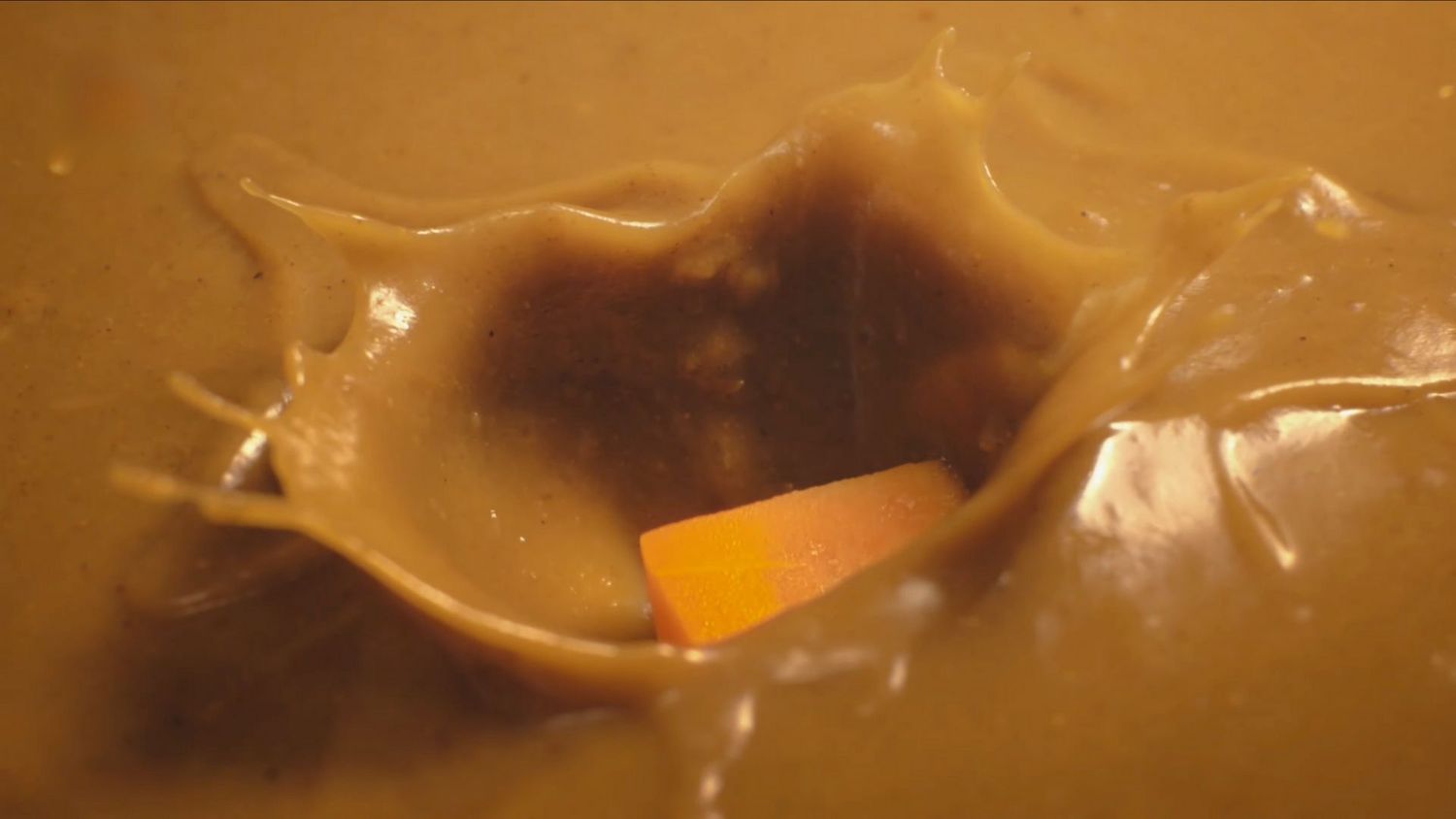 A close-up shot shows golden honey dripping and forming a glossy stream against a warm-toned background.