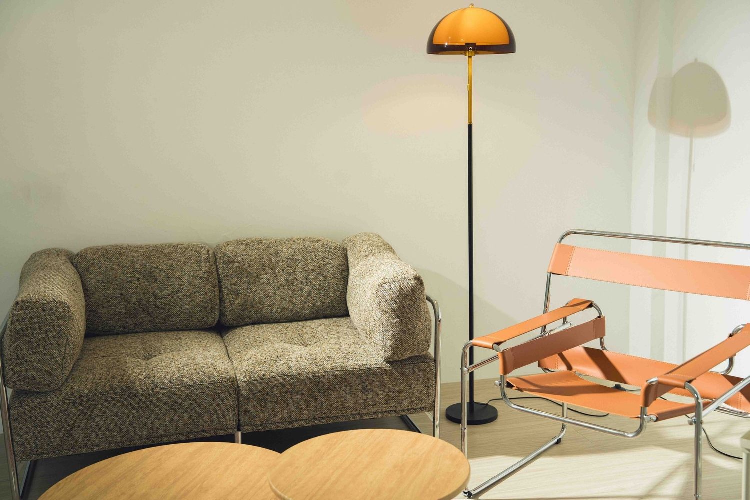 Modern living room with grey couch, orange floor lamp, coral chairs and round wooden coffee table.