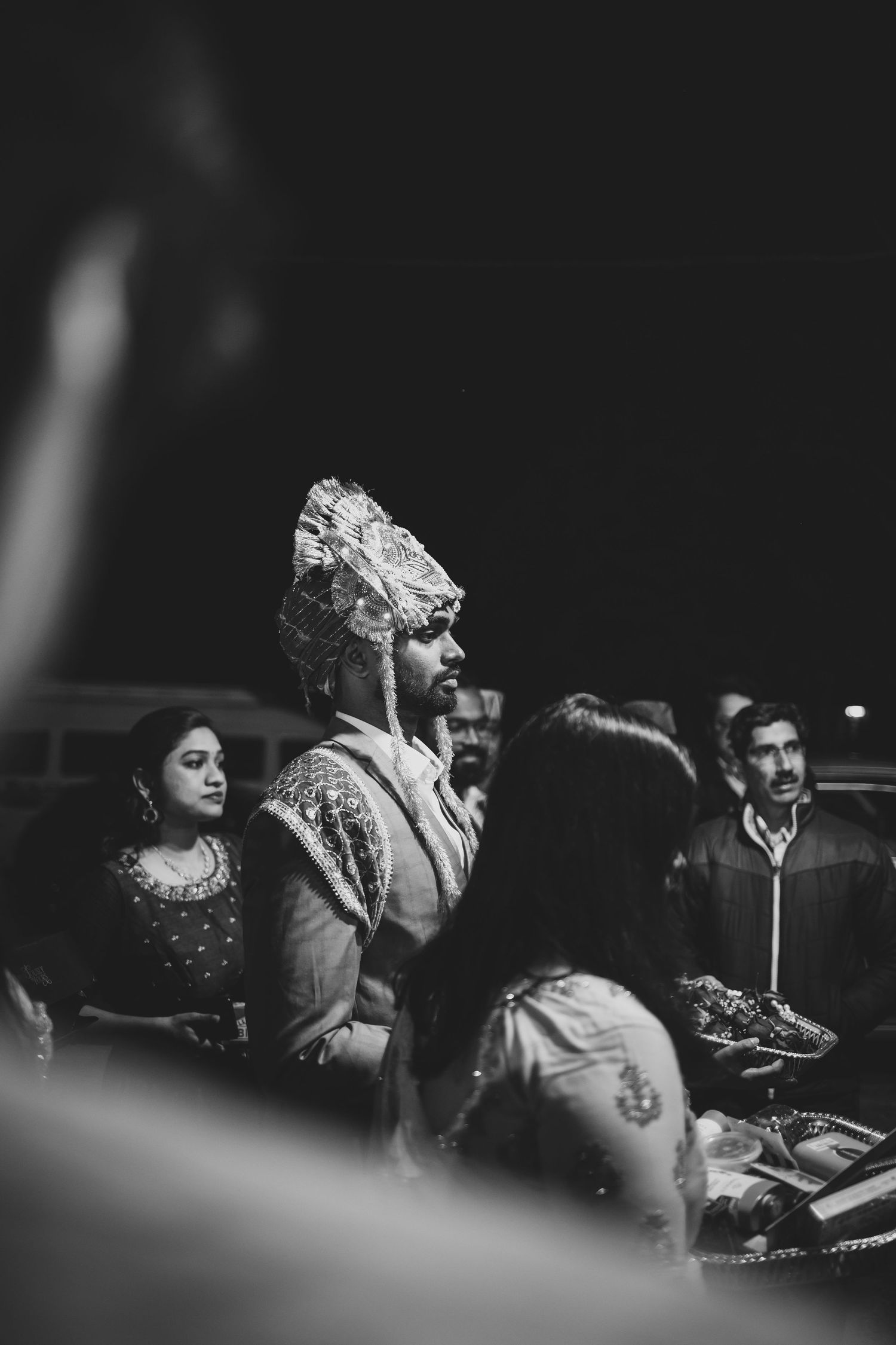 Groom in traditional Indian turban during wedding ceremony captured in black and white photography.