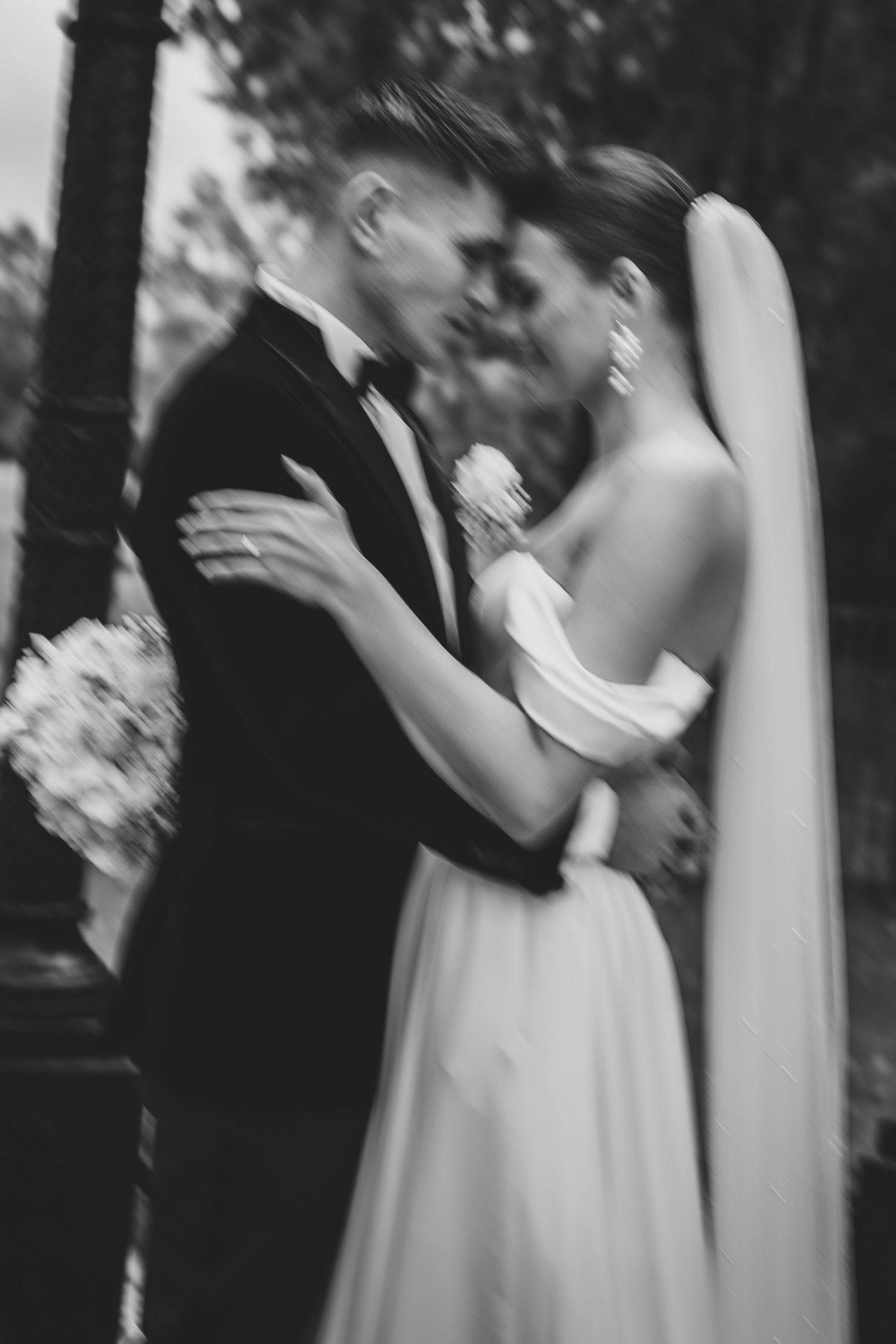 Black and white blurred artistic photo of bride and groom embracing tenderly on their wedding day.