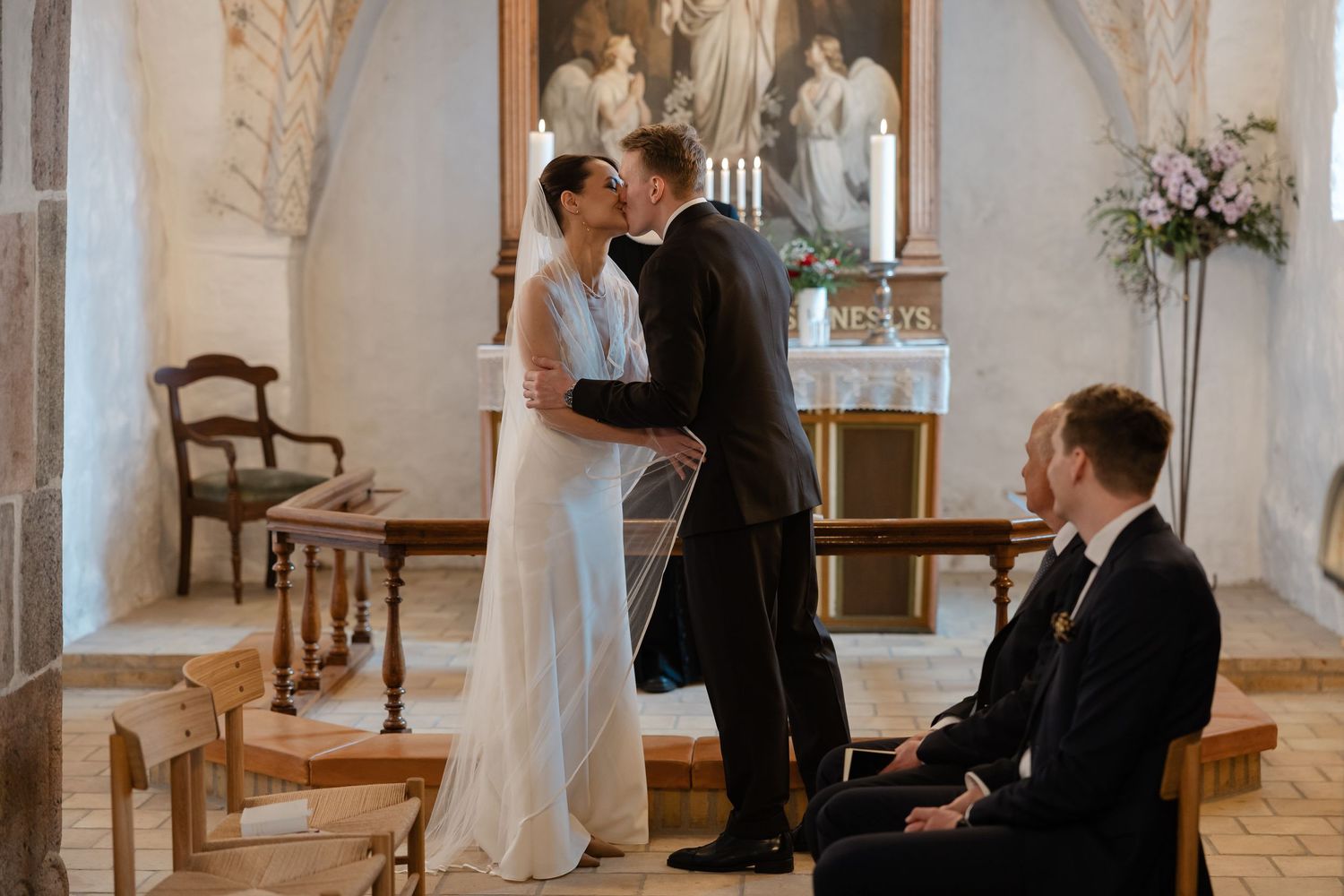 Newlyweds sharing a kiss at the altar in a historic church during their intimate wedding ceremony.